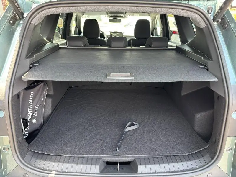 Vue arrière du coffre ouvert du Dacia Bigster blanc, avec cache-bagages et banquette arrière visible.