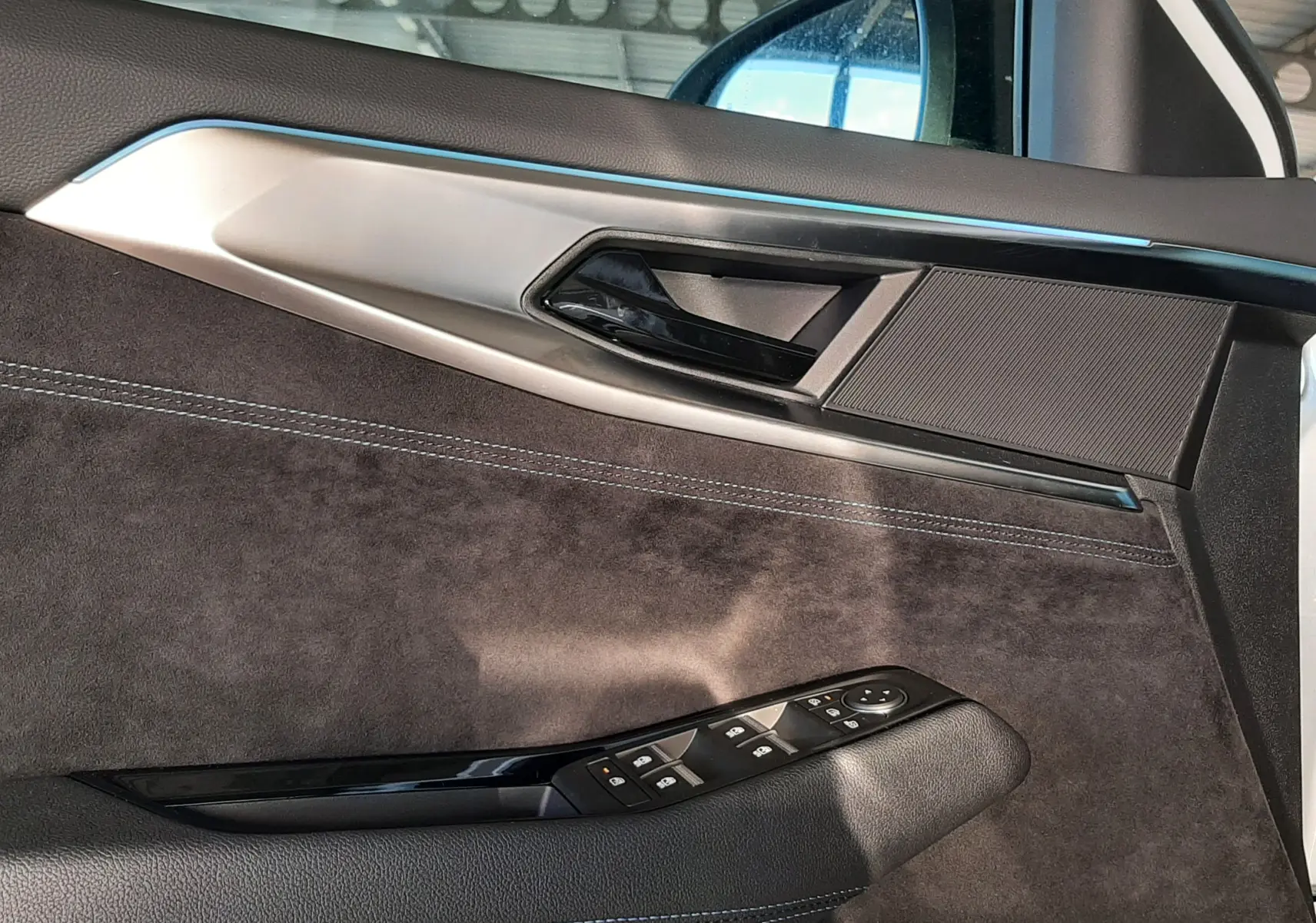 Vue intérieure côté gauche de la porte avant du Renault Austral blanc nacré, avec garniture noire et commandes de vitres.