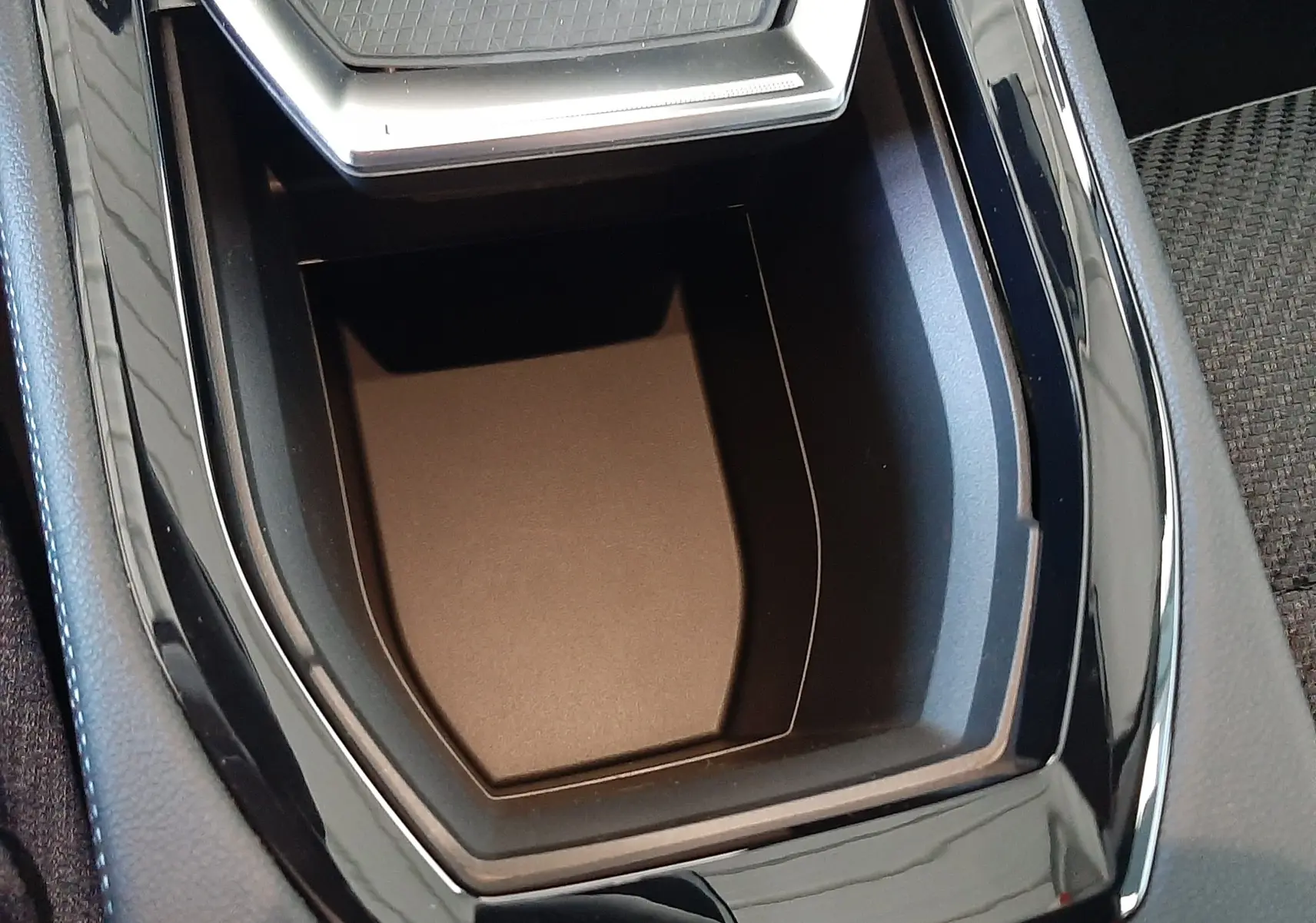 Vue rapprochée de la console centrale noire brillante du Renault Austral E-Tech avec espace de rangement et surface texturée.