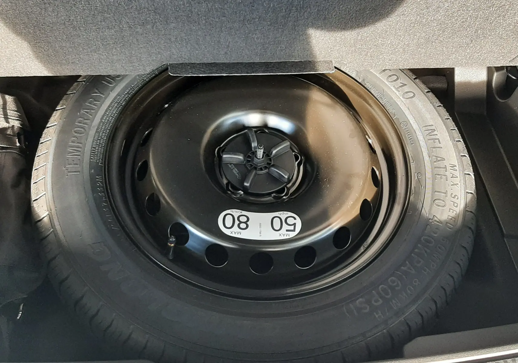Gros plan sur la roue de secours provisoire dans le coffre du Renault Austral blanc nacré 2025.