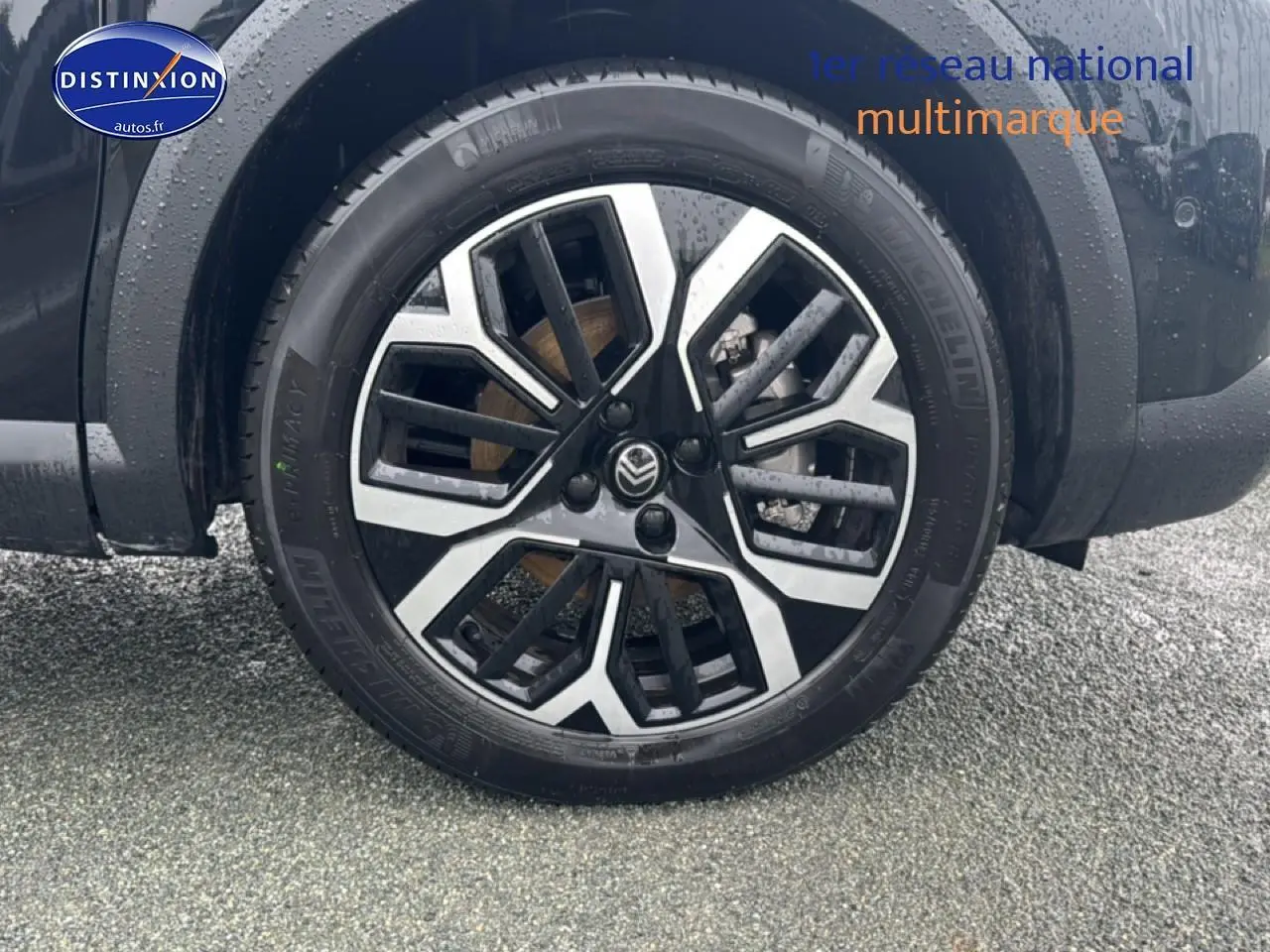 Gros plan sur la roue avant droite noire de la Citroën C4 hybride avec jante alu bicolore moderne.