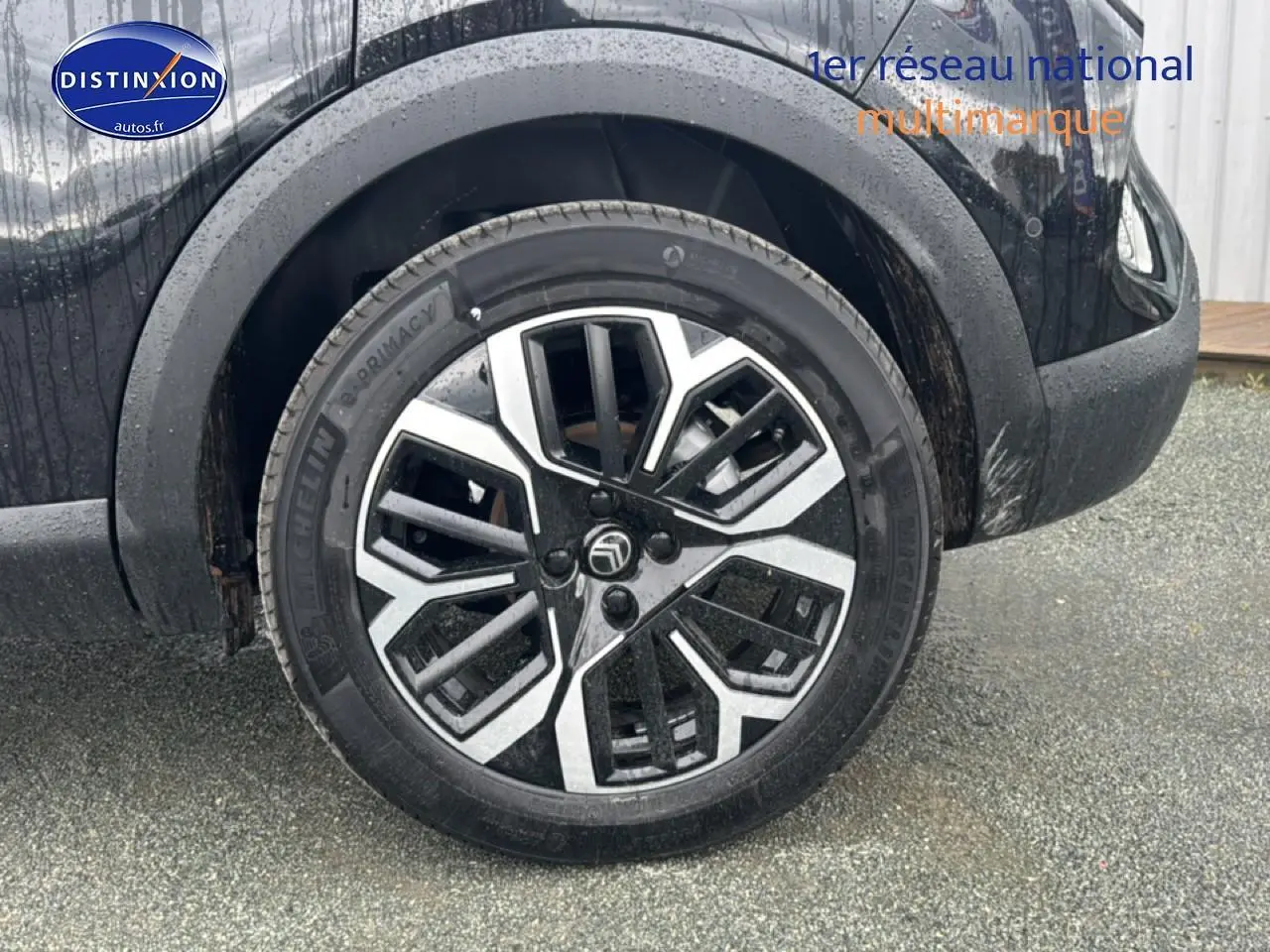 Gros plan sur la roue arrière droite noire d'une Citroën C4 1.2 hybride 2025 avec jante alu bicolore design.