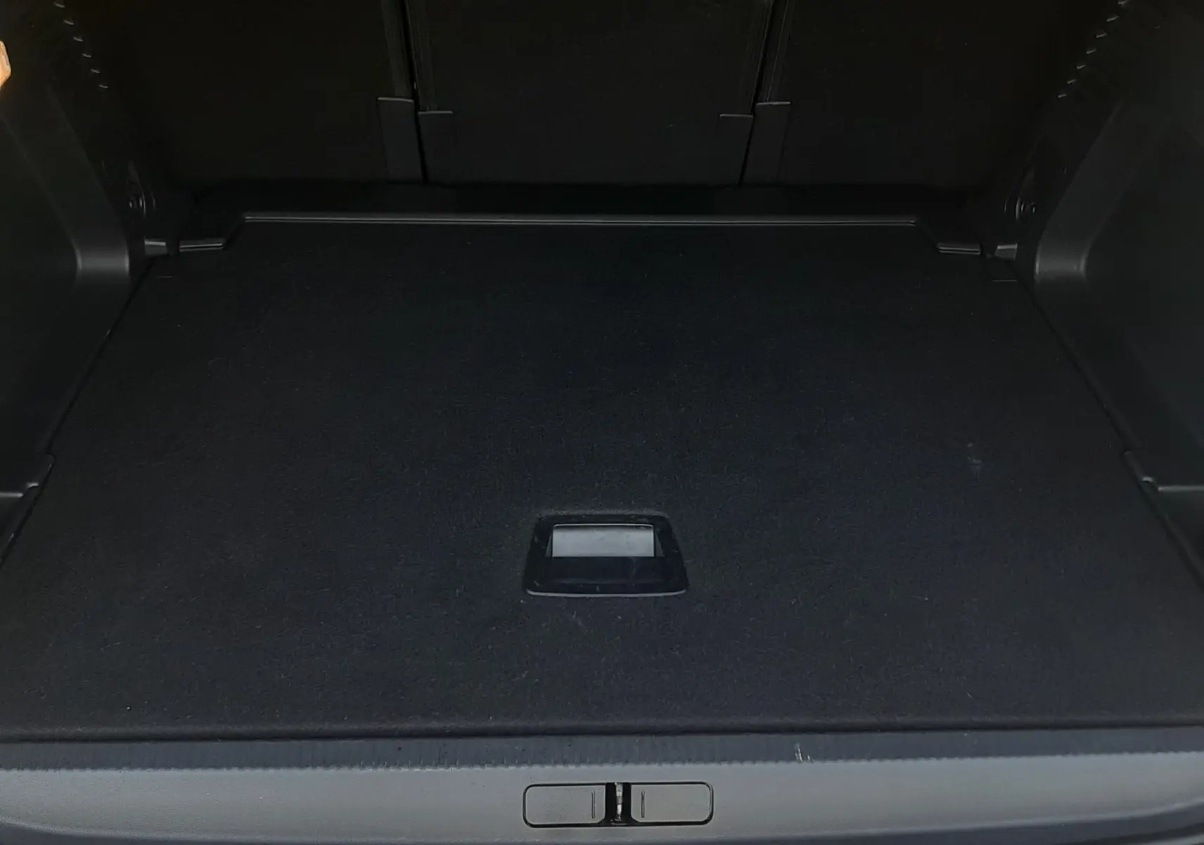 Coffre ouvert vu de l'arrière d'un Citroën C5 Aircross hybride gris platinium, espace de chargement vide et propre.