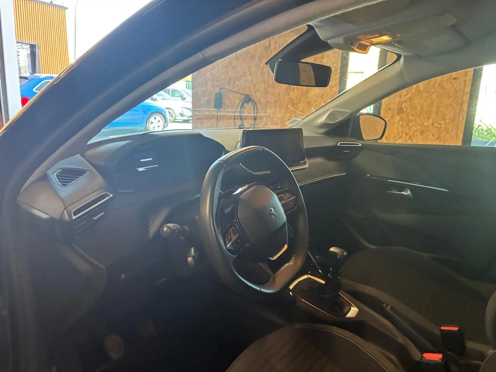 Intérieur noir de la Peugeot 208 1.5 BlueHDi 100 Style, vue côté conducteur montrant volant et console centrale.