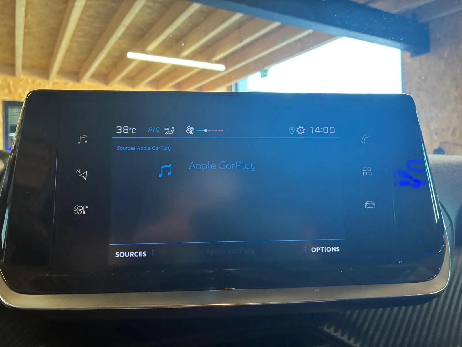 Écran tactile central du tableau de bord de la Peugeot 208 noir, affichant Apple CarPlay et la température à 38°C.