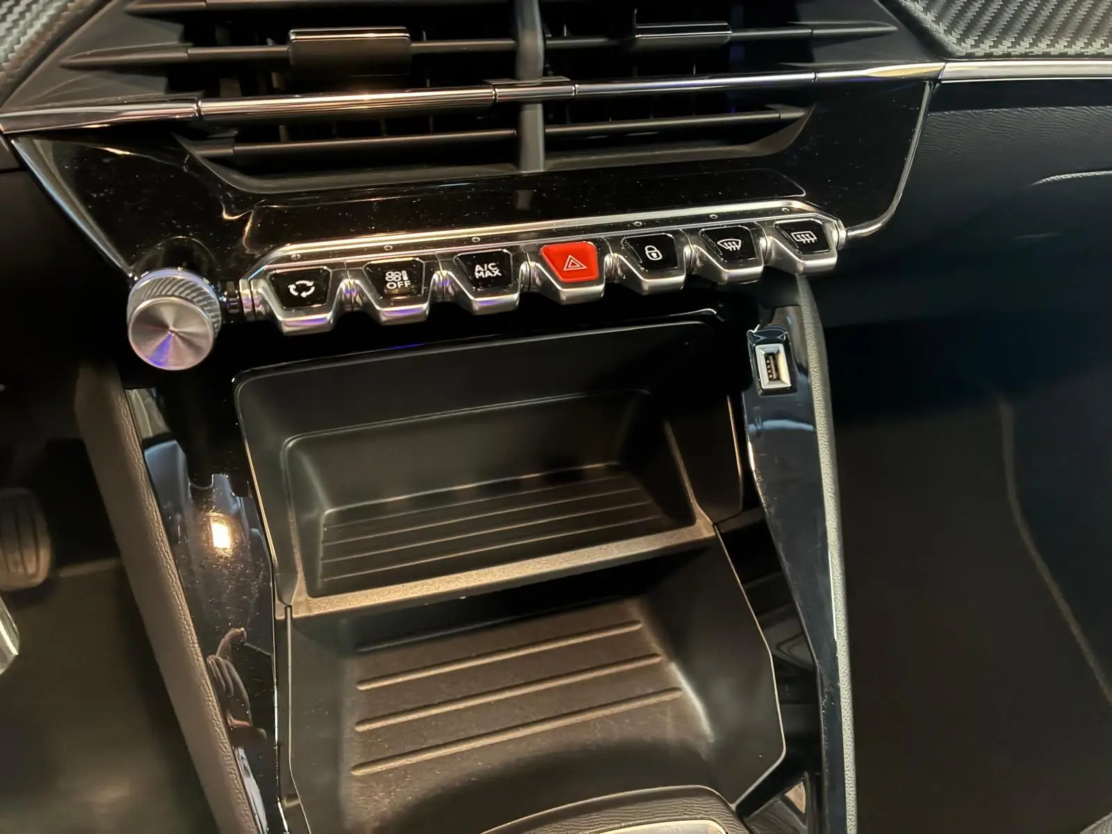 Gros plan sur la console centrale noire du Peugeot 208 1.5 BlueHDi 100 Style 2021 avec boutons de commande et port USB visible.