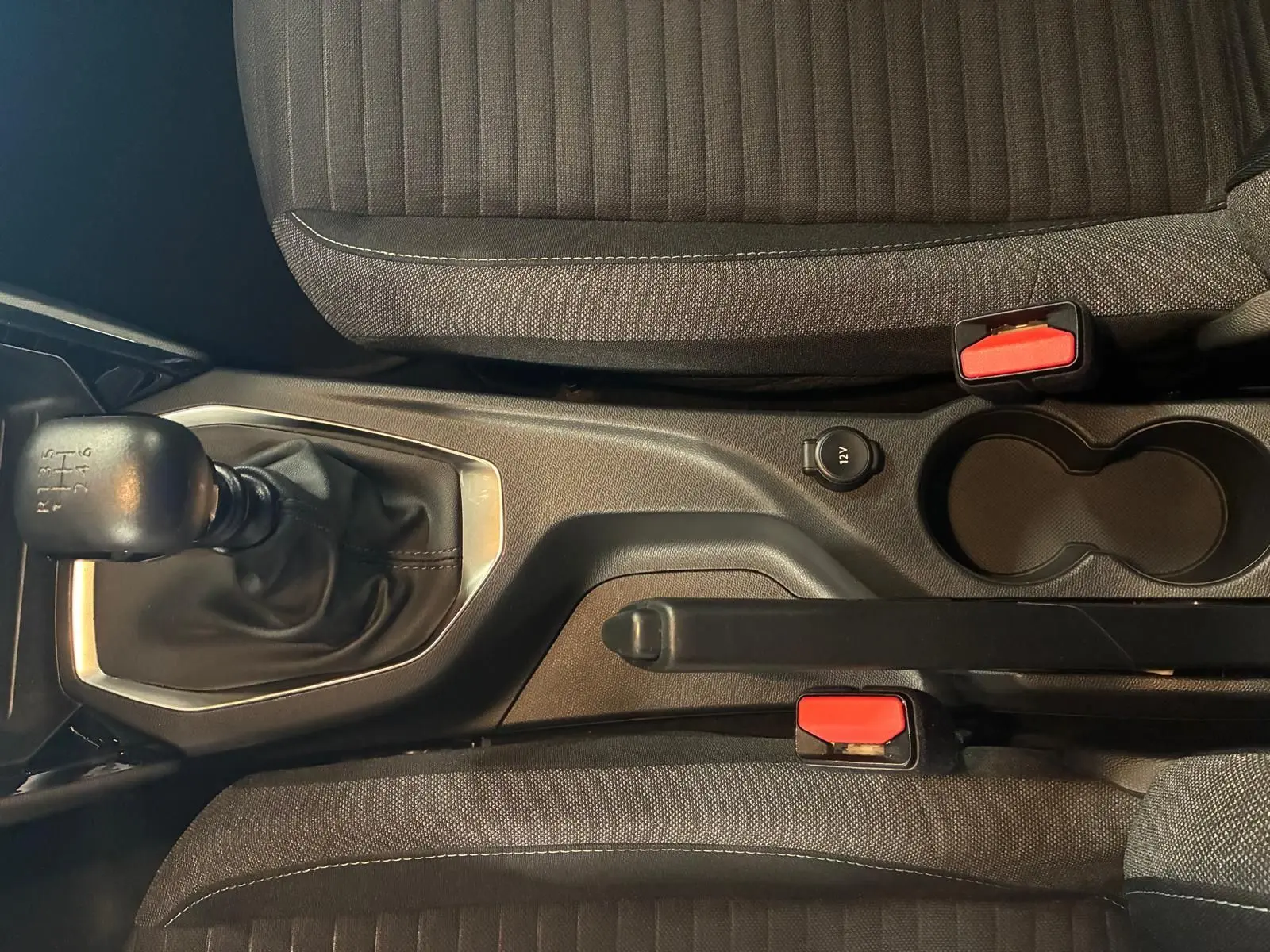 Vue intérieure en plongée sur la console centrale de la Peugeot 208 noire, montrant levier de vitesse manuel et frein à main.