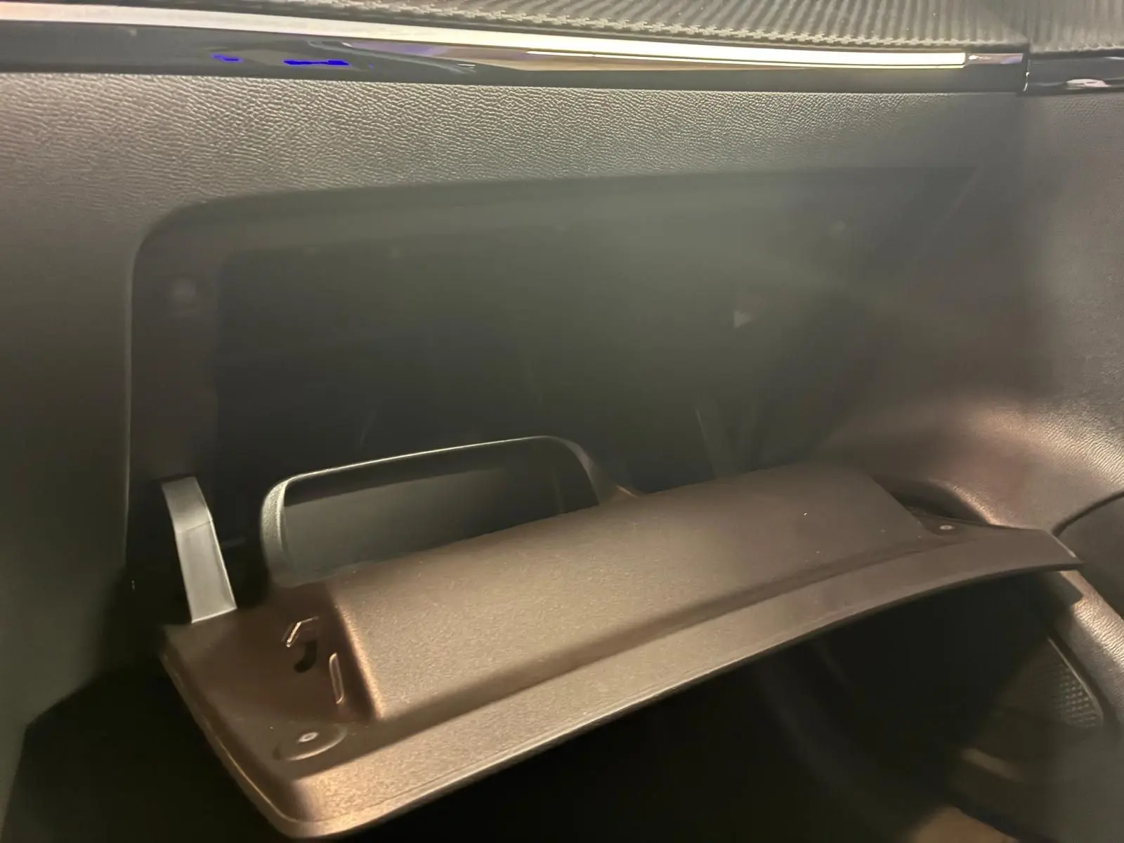Intérieur de la Peugeot 208 1.5 BlueHDi 100 Style 2021, boîte à gants ouverte côté passager, finition noire.