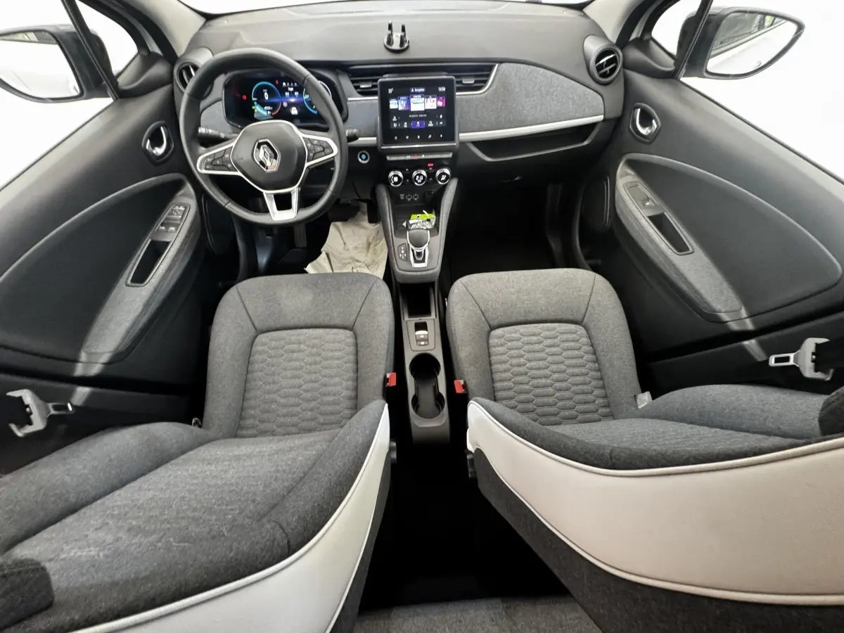 Vue intérieure avant de la Renault ZOE Iconic R135 2022 avec sièges gris et tableau de bord central tactile.