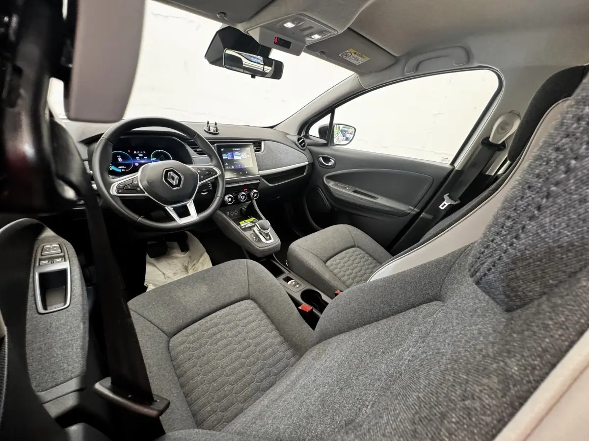 Vue intérieure avant droite de la Renault ZOE Iconic R135 2022 avec sièges gris et tableau de bord moderne.