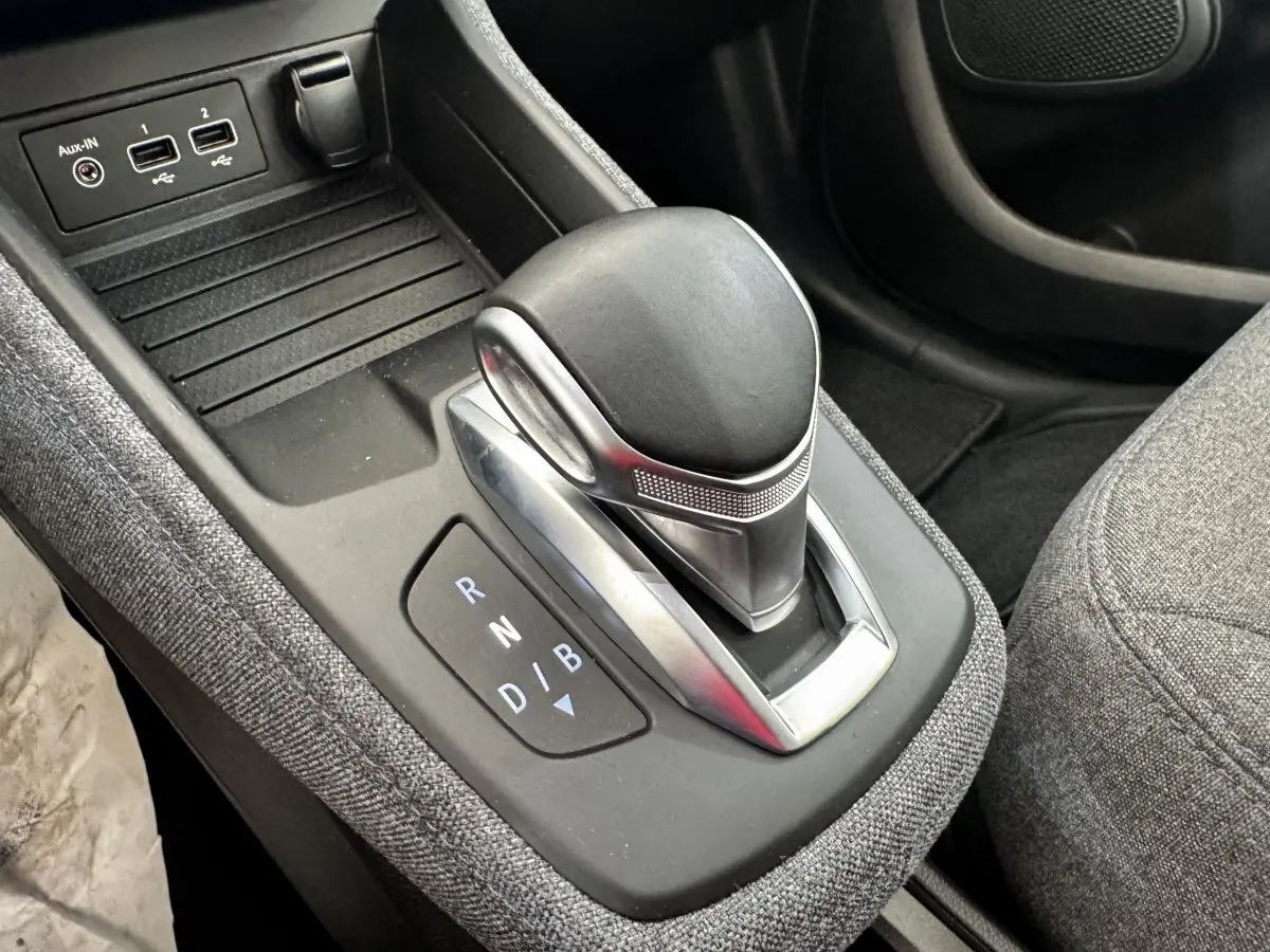 Le levier de vitesses automatique noir et argenté de la Renault ZOE Iconic R135, avec ports USB et tissu gris autour.