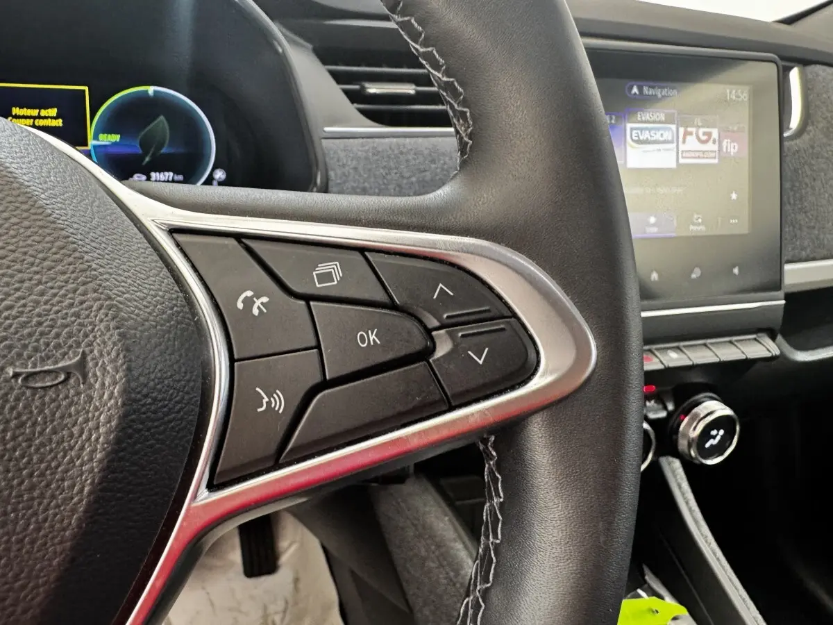 Gros plan sur le volant noir avec commandes multifonctions et écran tactile du tableau de bord de la Renault ZOE Iconic R135 blanche.