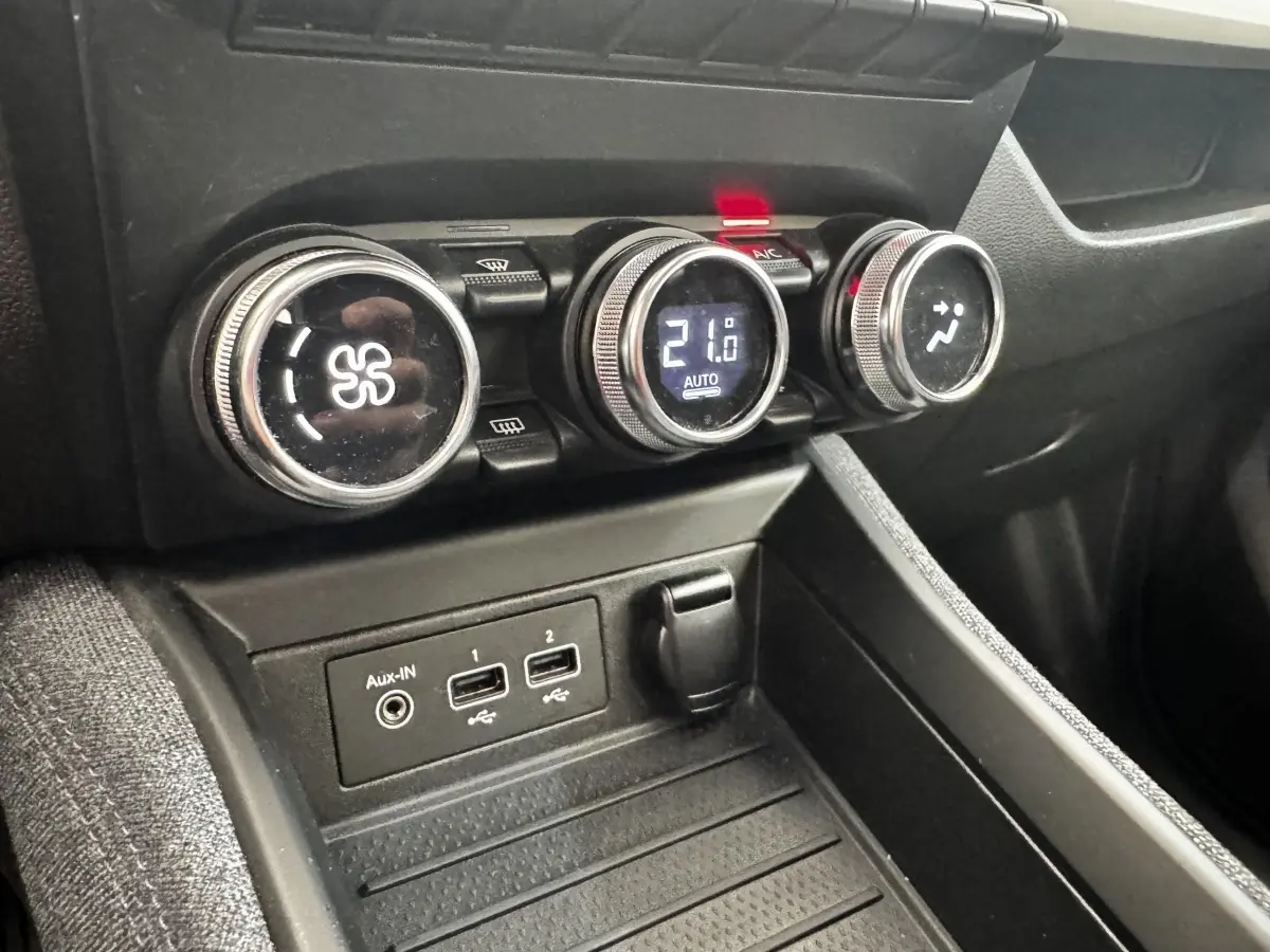 Gros plan sur la console centrale de la Renault ZOE blanche, montrant les commandes de climatisation et ports USB.