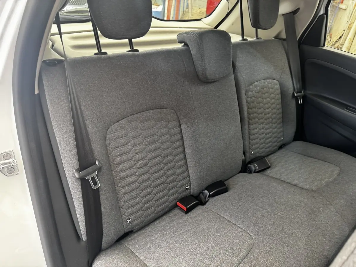 Vue intérieure sur la banquette arrière grise de la Renault ZOE blanche, avec appuie-têtes et ceintures visibles.