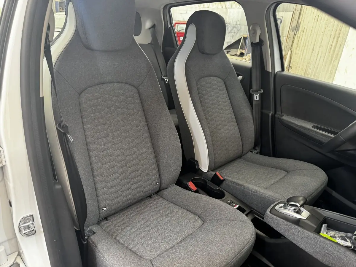 Vue intérieure côté gauche sur les sièges avant gris de la Renault ZOE Iconic R135 blanche 2022.