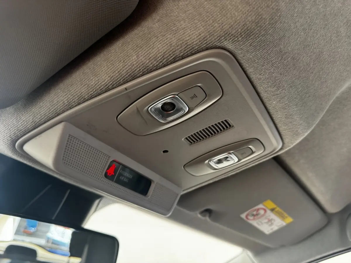 Vue intérieure du plafonnier gris clair de la Renault ZOE Iconic R135 avec éclairages et indicateur airbag passager.