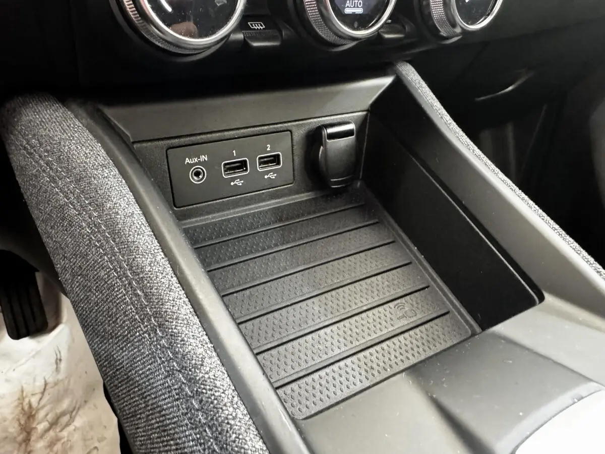 Gros plan sur la console centrale noire de la Renault ZOE blanche, montrant ports USB, prise Aux-IN et rangement.