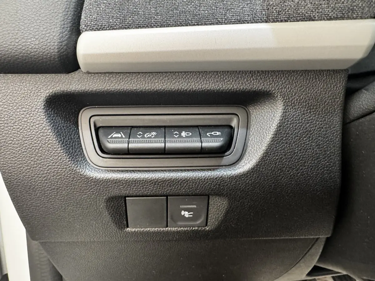 Gros plan sur les boutons de commande noirs intégrés dans la console intérieure noire et grise de la Renault ZOE blanche Iconic R135.