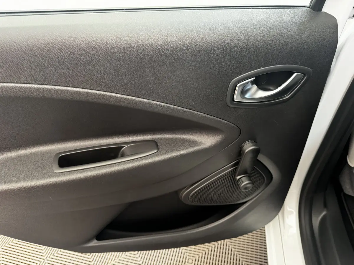 Gros plan sur la porte arrière droite blanche de la Renault ZOE Iconic R135 avec manivelle de vitre noire.