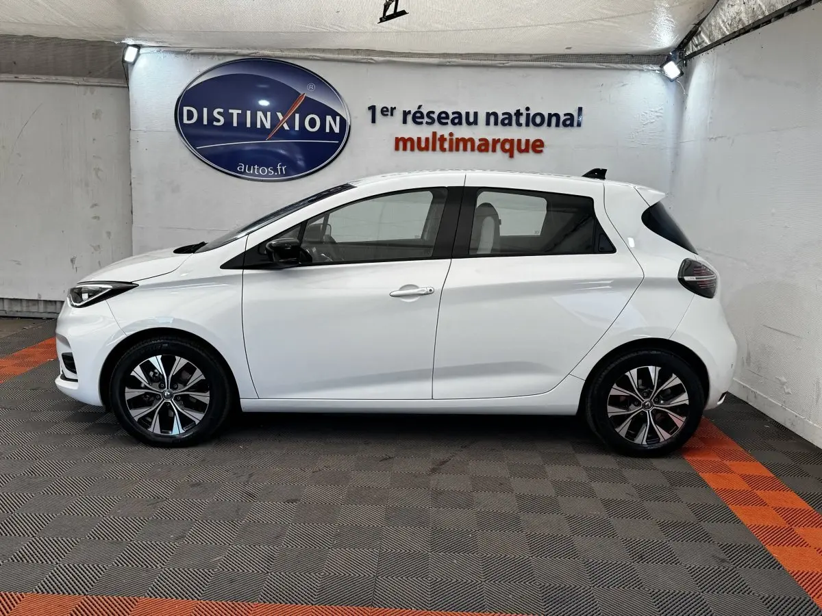 Profil droit de la Renault ZOE Iconic R135 blanche 2022, avec jantes alliage et vitres teintées.