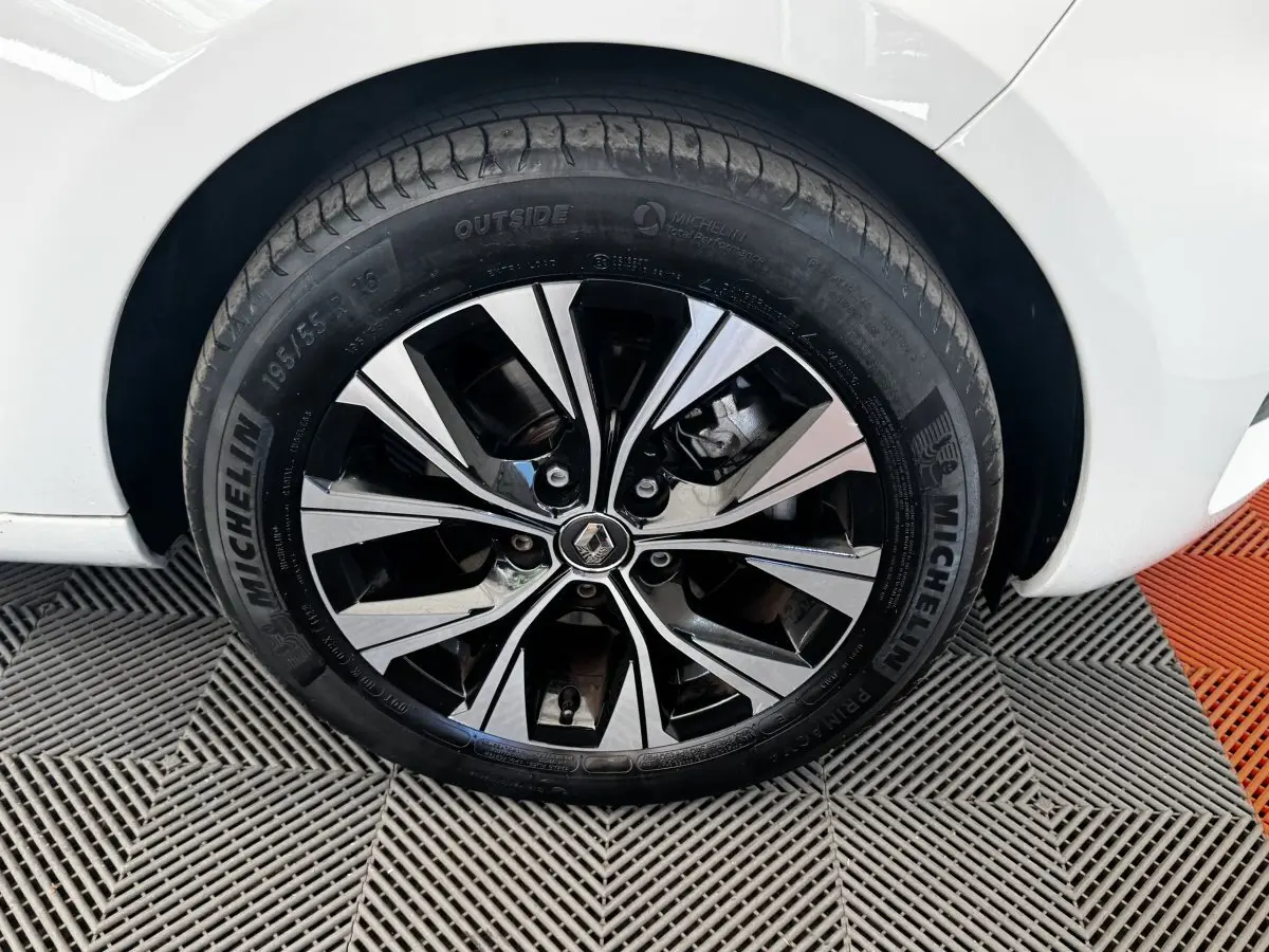 Gros plan sur la roue avant droite de la Renault ZOE blanche, jante alliage bicolore avec logo Renault au centre.