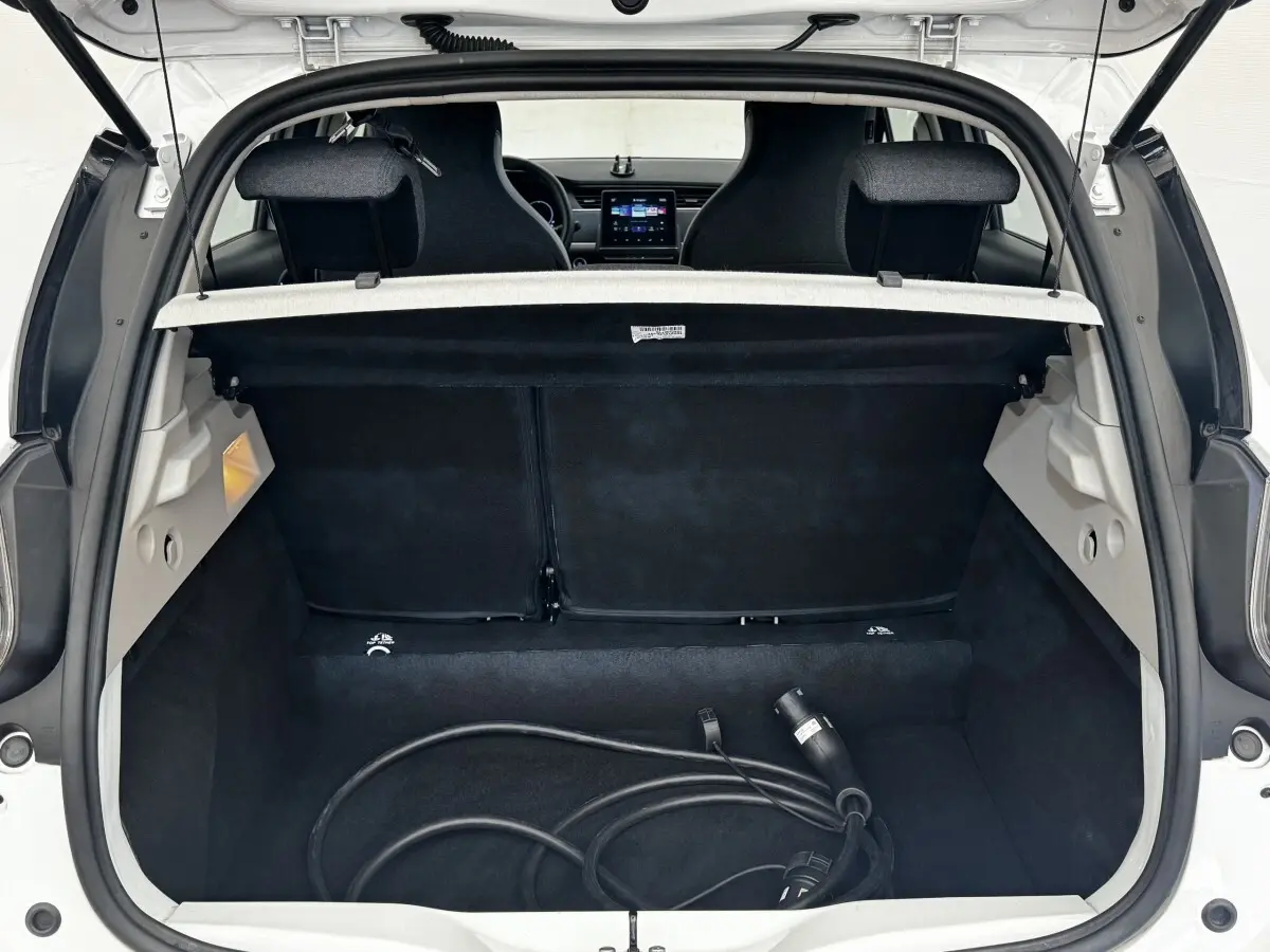 Vue arrière du coffre ouvert d'une Renault ZOE blanche, avec câble de recharge électrique visible à l'intérieur.