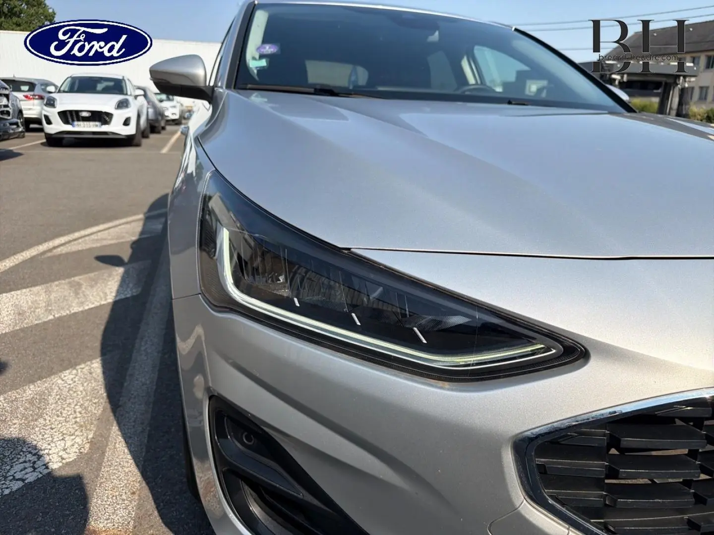 Gros plan sur le phare avant gauche et la calandre chromée d'une Ford Focus gris lunaire métallisé 2023.