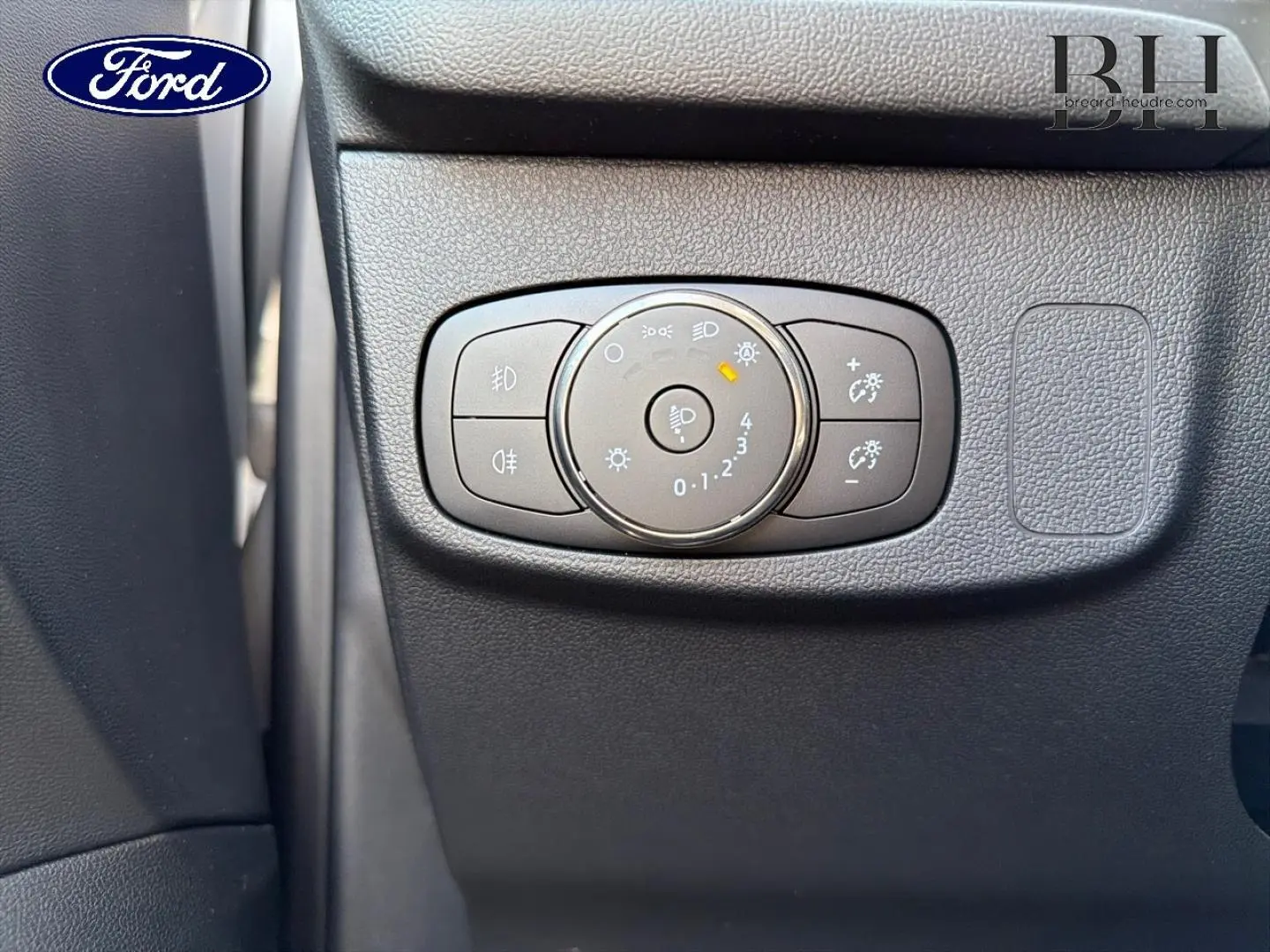 Gros plan sur la commande d'éclairage noire à gauche du tableau de bord d'une Ford Focus 2023 gris lunaire métallisé.