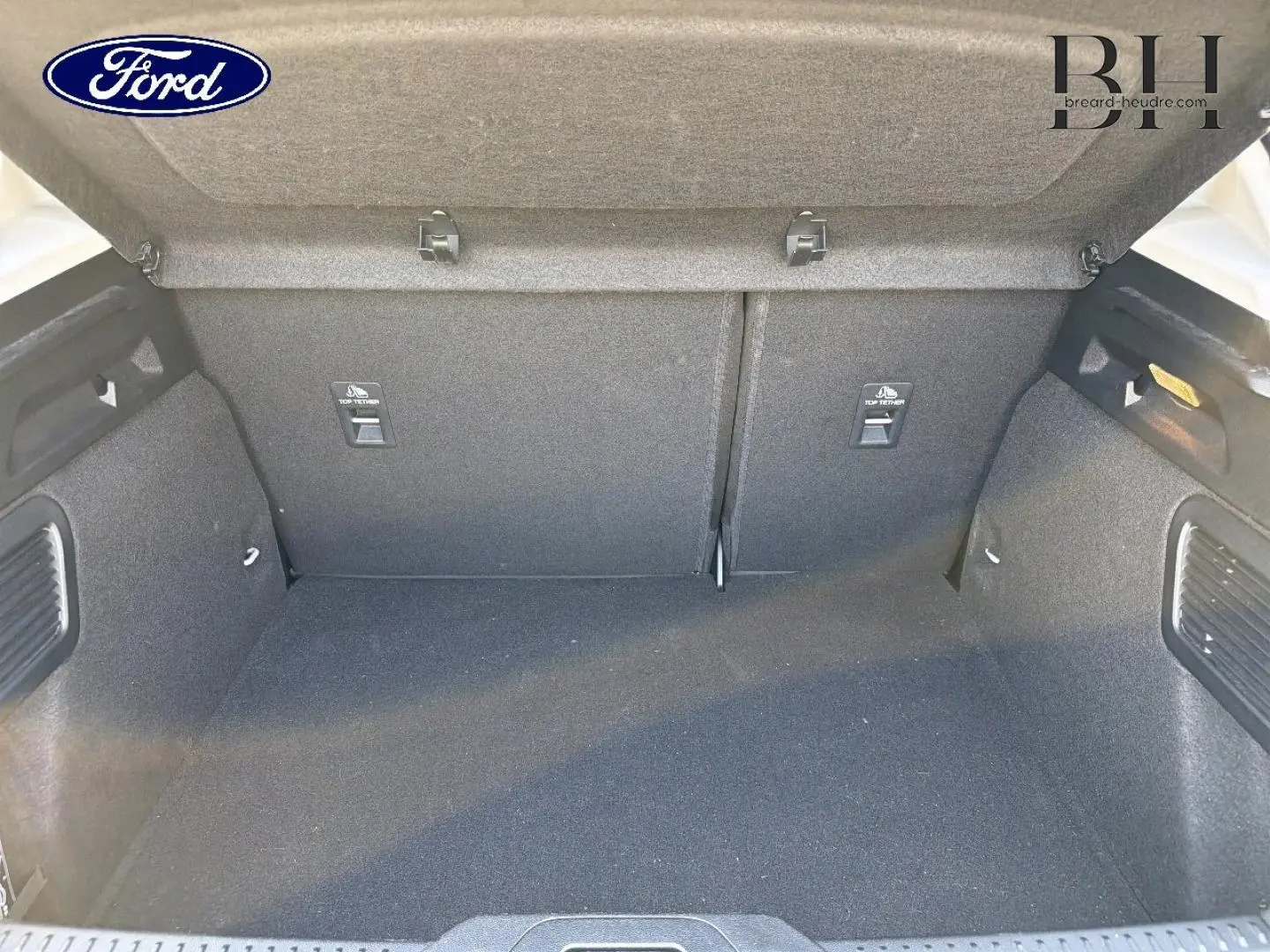 Coffre ouvert de Ford Focus 2023 gris lunaire, vue intérieure montrant l'espace de chargement et les fixations Isofix.