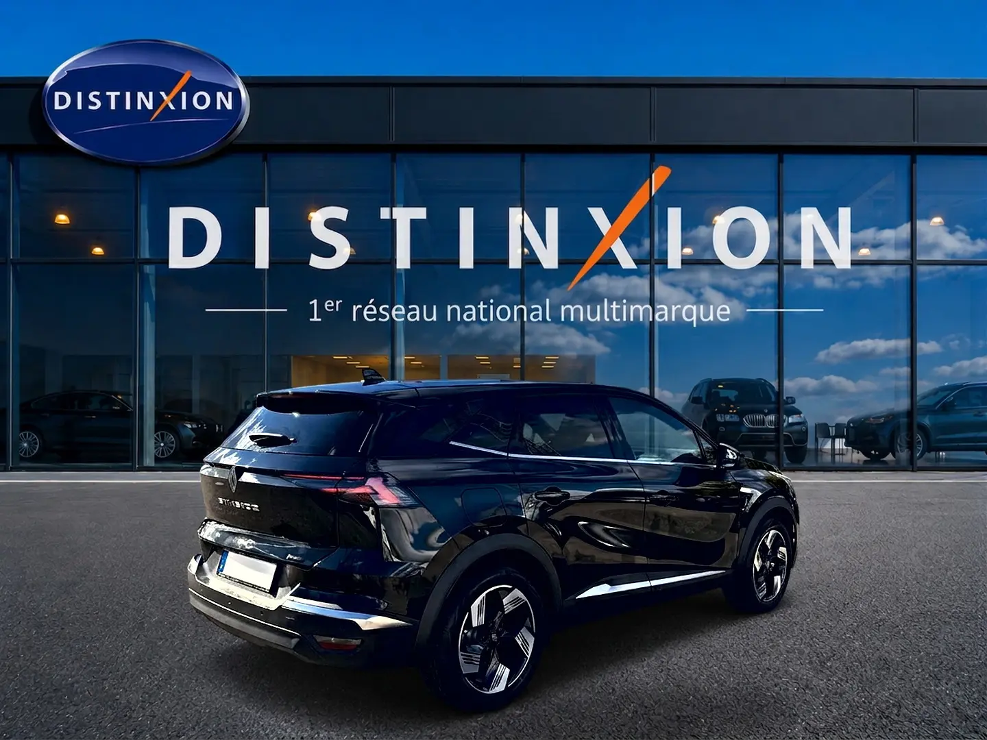 Vue 3/4 arrière droite d’un Renault Symbioz noir étoile avec jantes alu, garé devant une vitrine Distinxion.