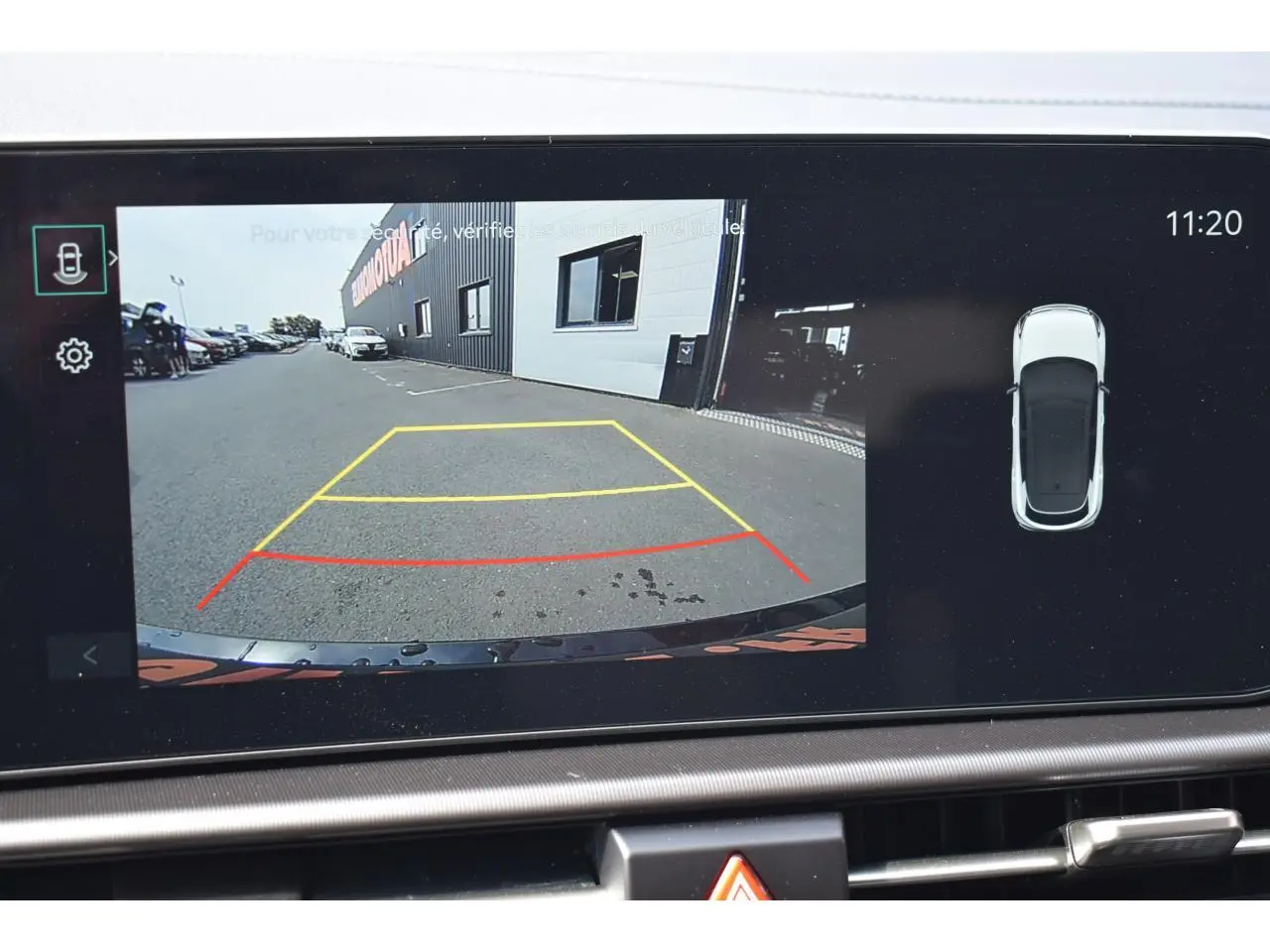 Écran tactile affichant la caméra de recul du Kia Sportage noir, vue arrière avec lignes de guidage colorées.