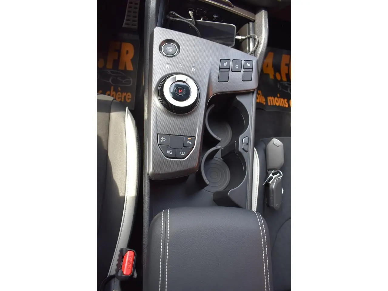 Vue plongeante sur la console centrale noire du Kia Sportage 2026 hybride avec commandes de sièges chauffants et frein électrique.