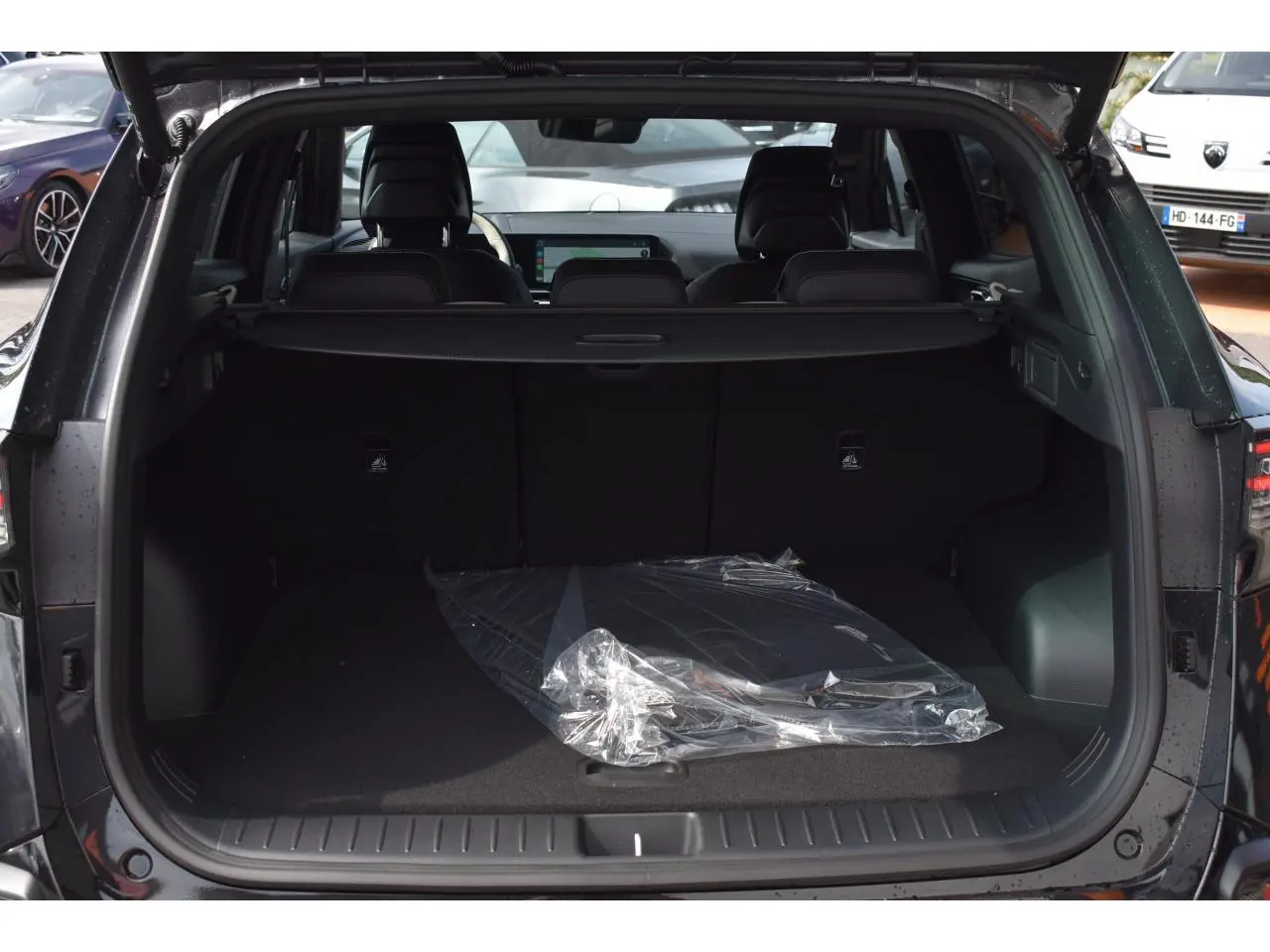 Coffre ouvert vu de l’arrière d’un Kia Sportage noir 2026, avec plancher plat et cache-bagages visible.