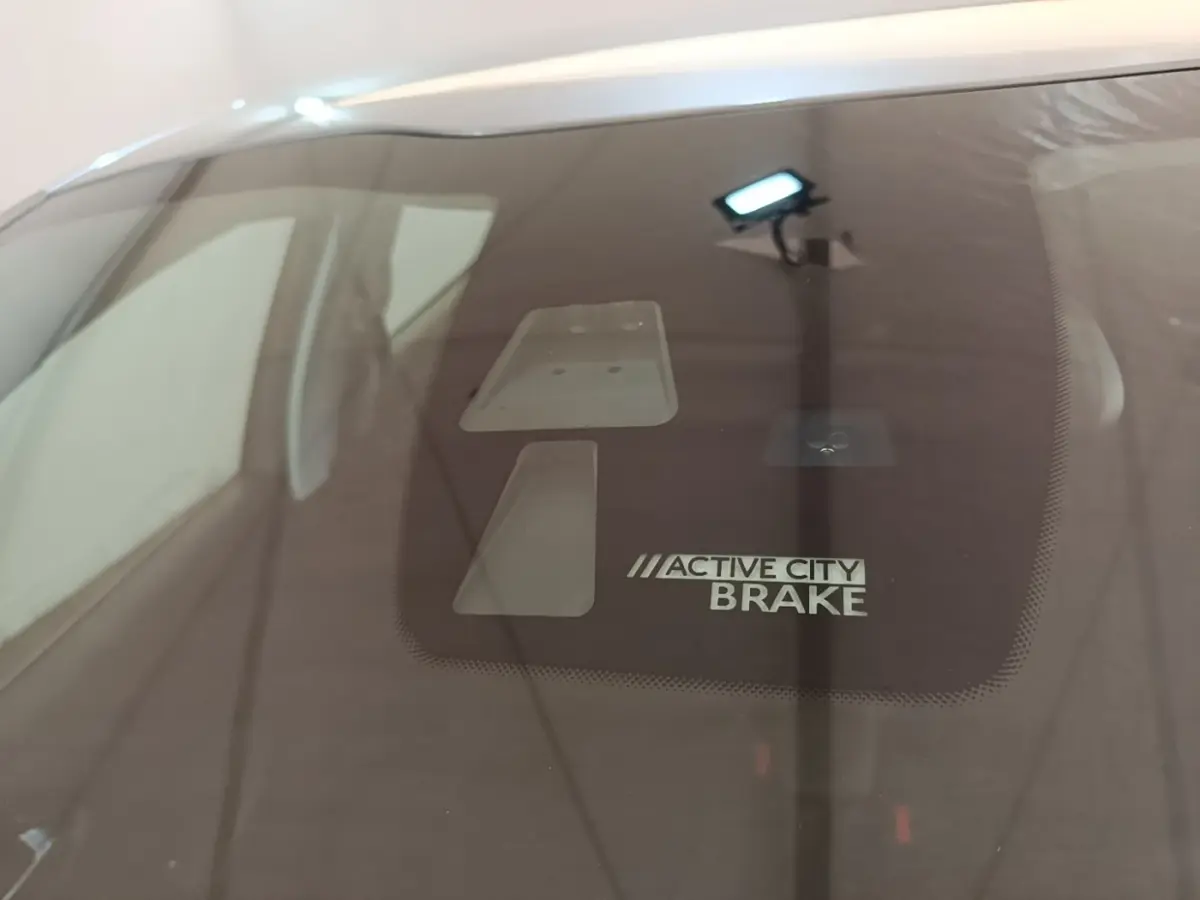 Gros plan sur le pare-brise d’une Peugeot 208 gris clair, mettant en valeur le système Active City Brake.