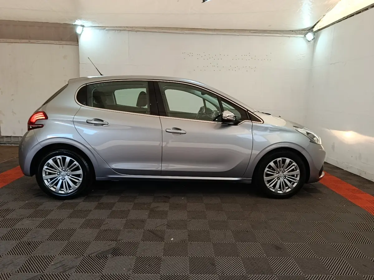 Peugeot 208 Puretech 82 Allure gris clair vue de profil côté gauche dans un garage éclairé.