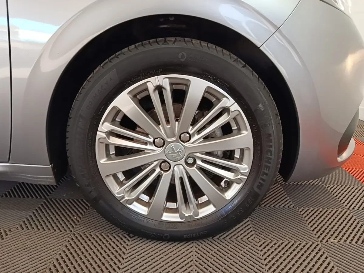 Gros plan sur la roue avant droite gris clair d’une Peugeot 208 Puretech 82 Allure avec jante alliage multibranches.