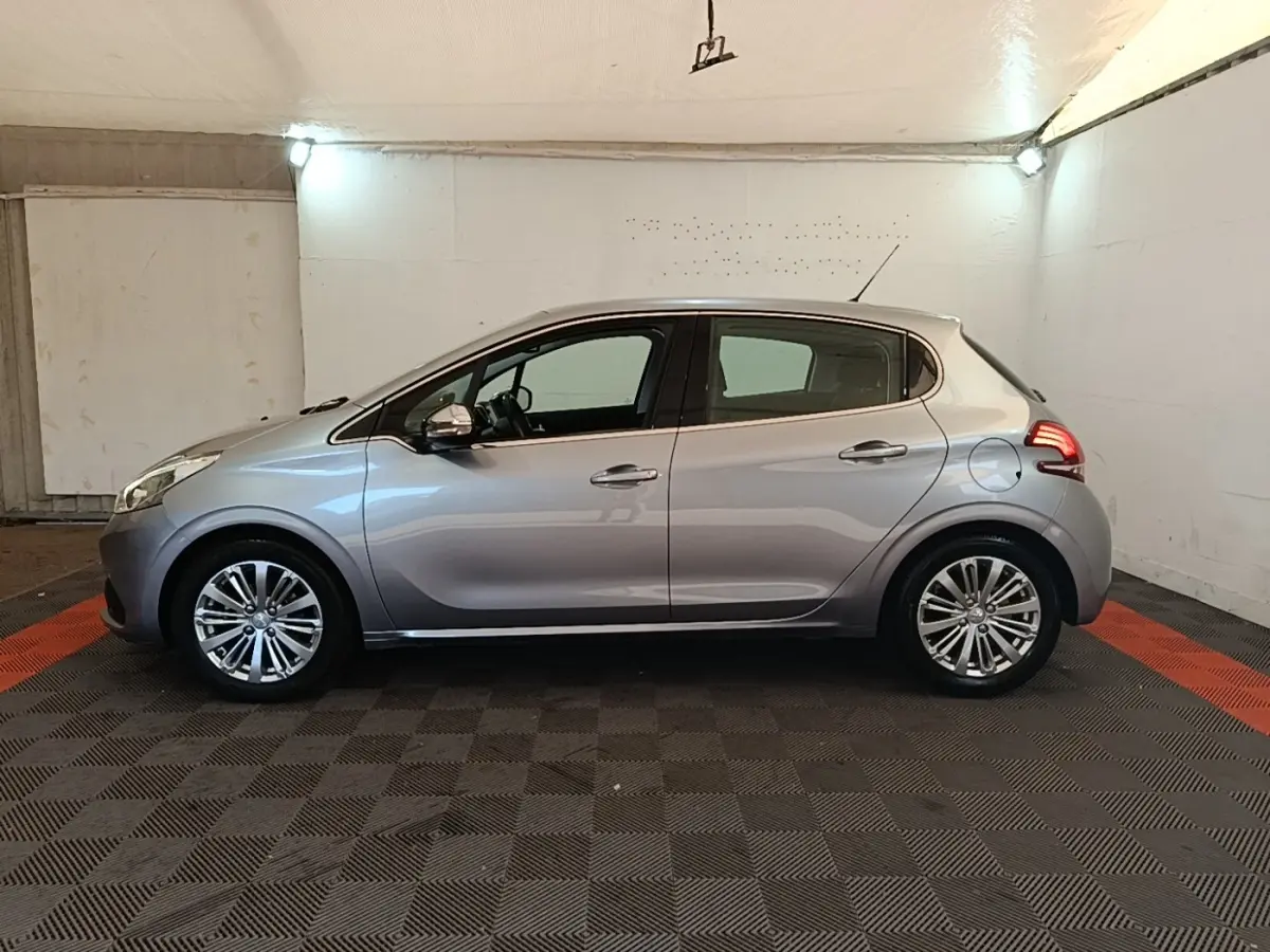 Peugeot 208 Puretech 82 Allure gris clair vue de profil côté gauche dans un garage éclairé.