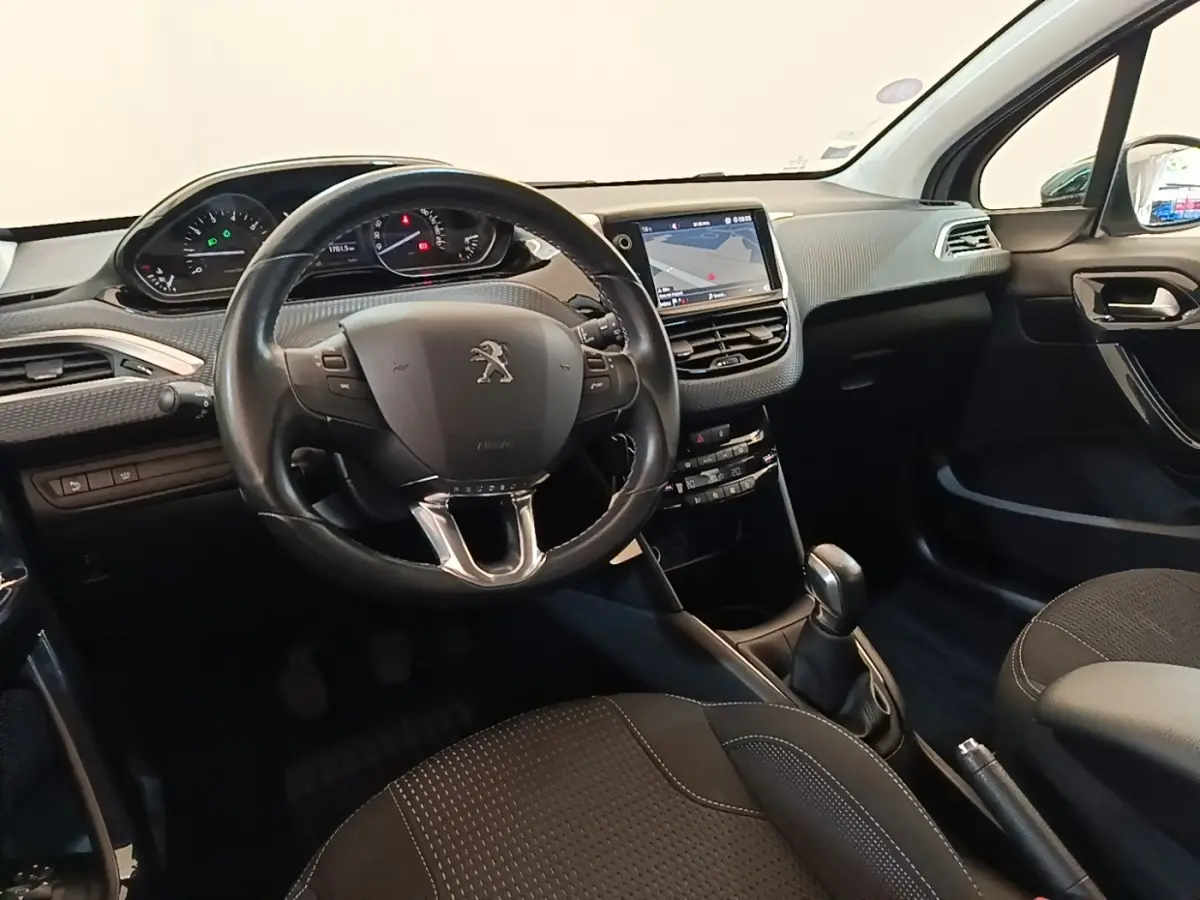 Vue intérieure avant de la Peugeot 208 Puretech 82 Allure 2019, tableau de bord noir avec écran tactile et volant cuir.