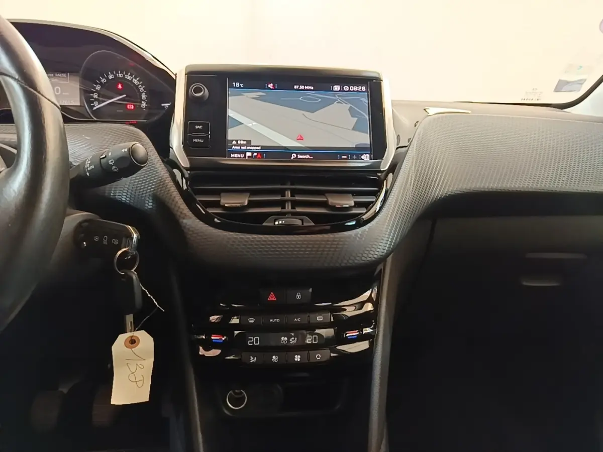 Vue intérieure centrée sur la console tactile et le tableau de bord de la Peugeot 208 gris clair, version Puretech 82 Allure.