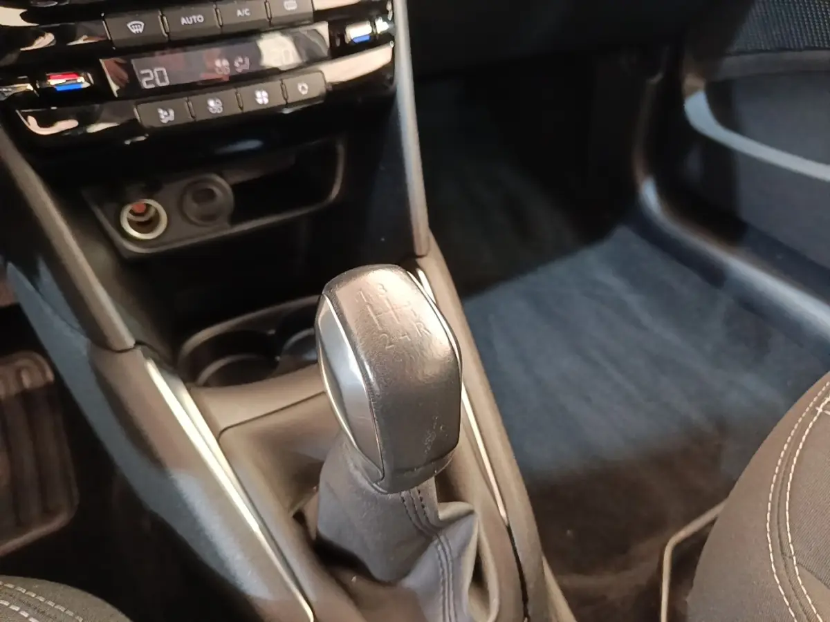 Gros plan sur le levier de vitesses manuel noir de la Peugeot 208 Puretech 82 Allure, intérieur gris foncé.