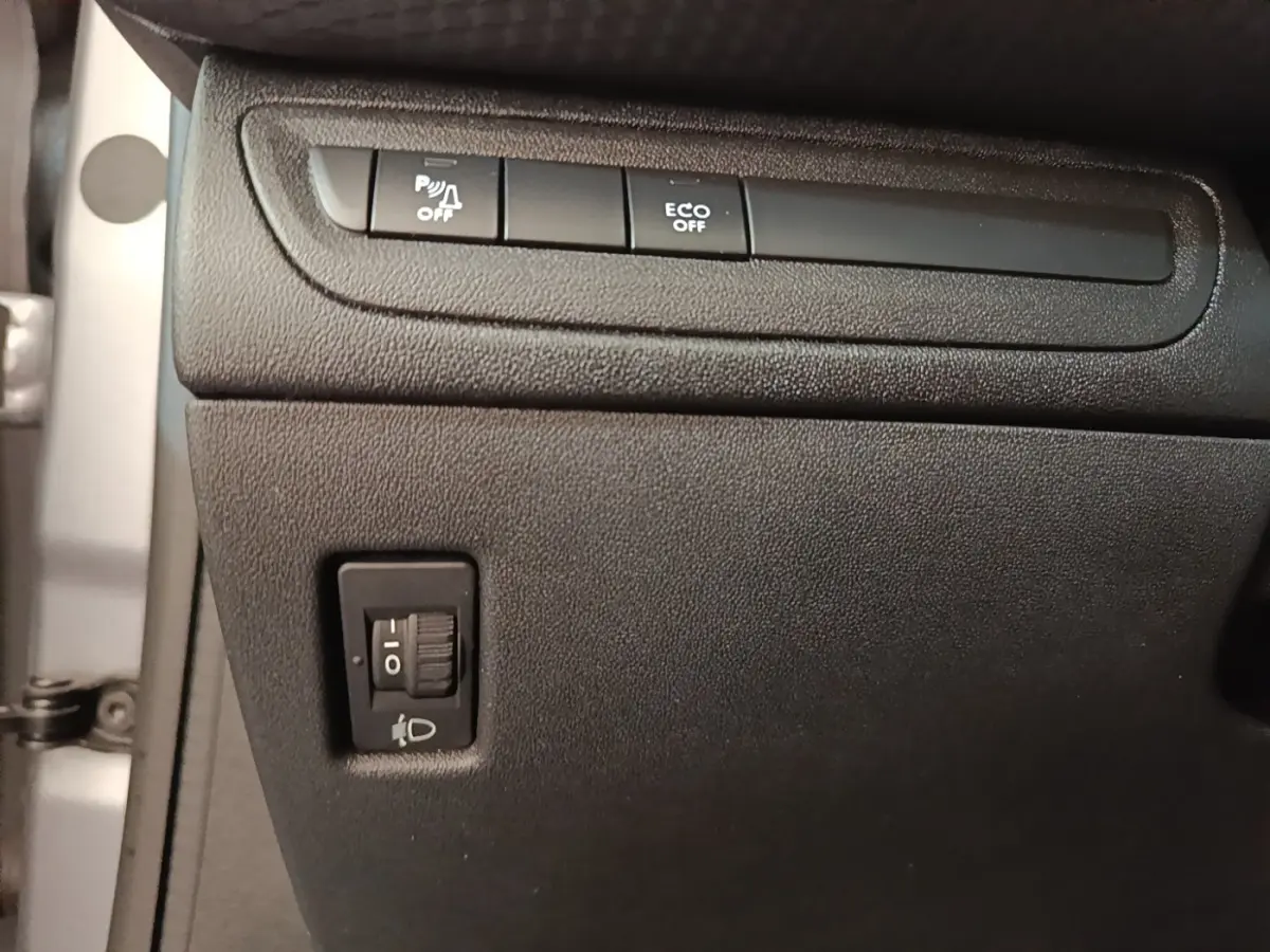 Détail intérieur montrant les commandes de désactivation du radar de recul et d'activation Eco sur Peugeot 208 gris clair.