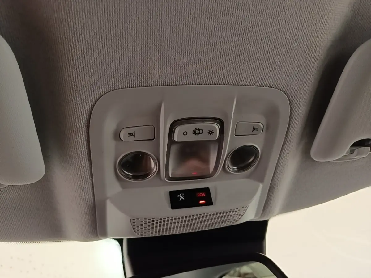 Vue intérieure du plafonnier de la Peugeot 208 gris clair, avec commandes d’éclairage et bouton SOS éclairé rouge.