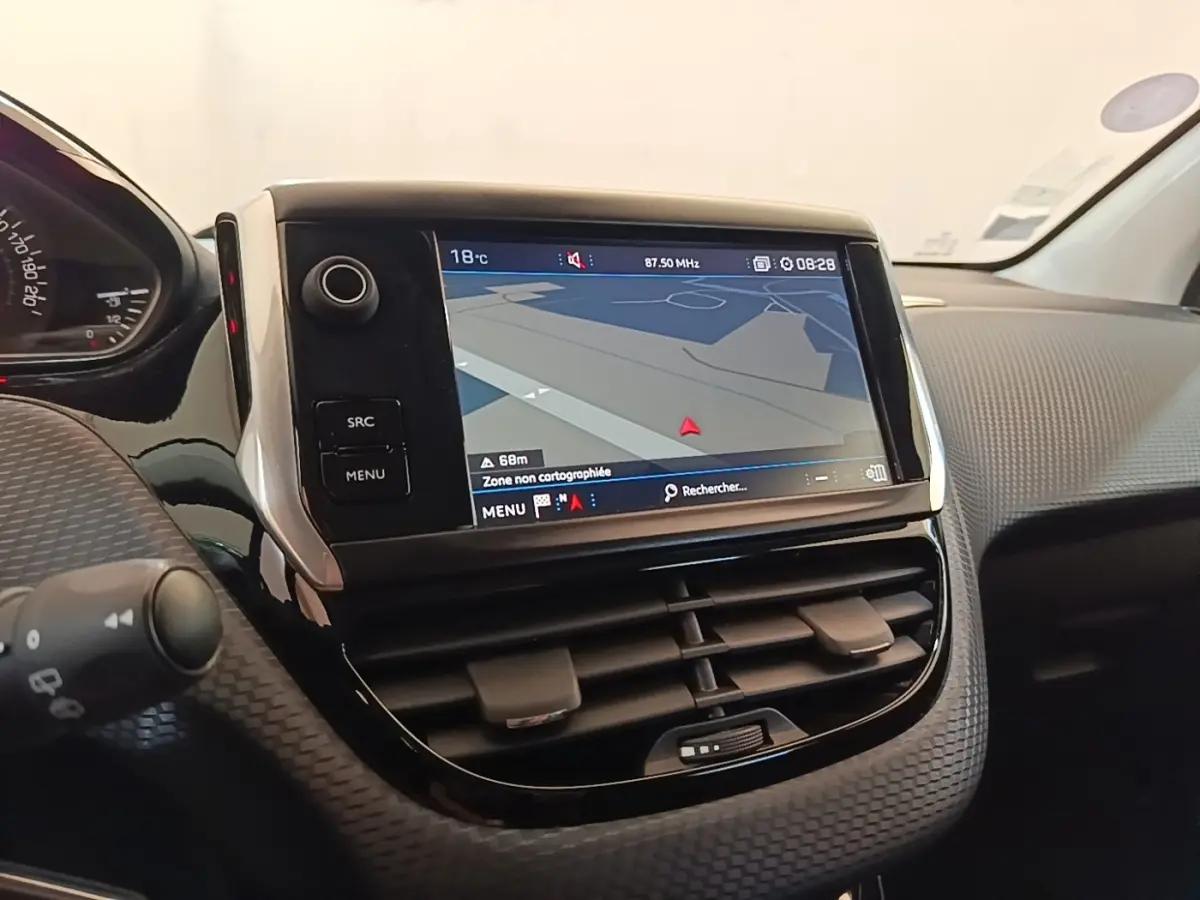 Gros plan sur l’écran tactile central et la console noire texturée du tableau de bord de la Peugeot 208 gris clair.