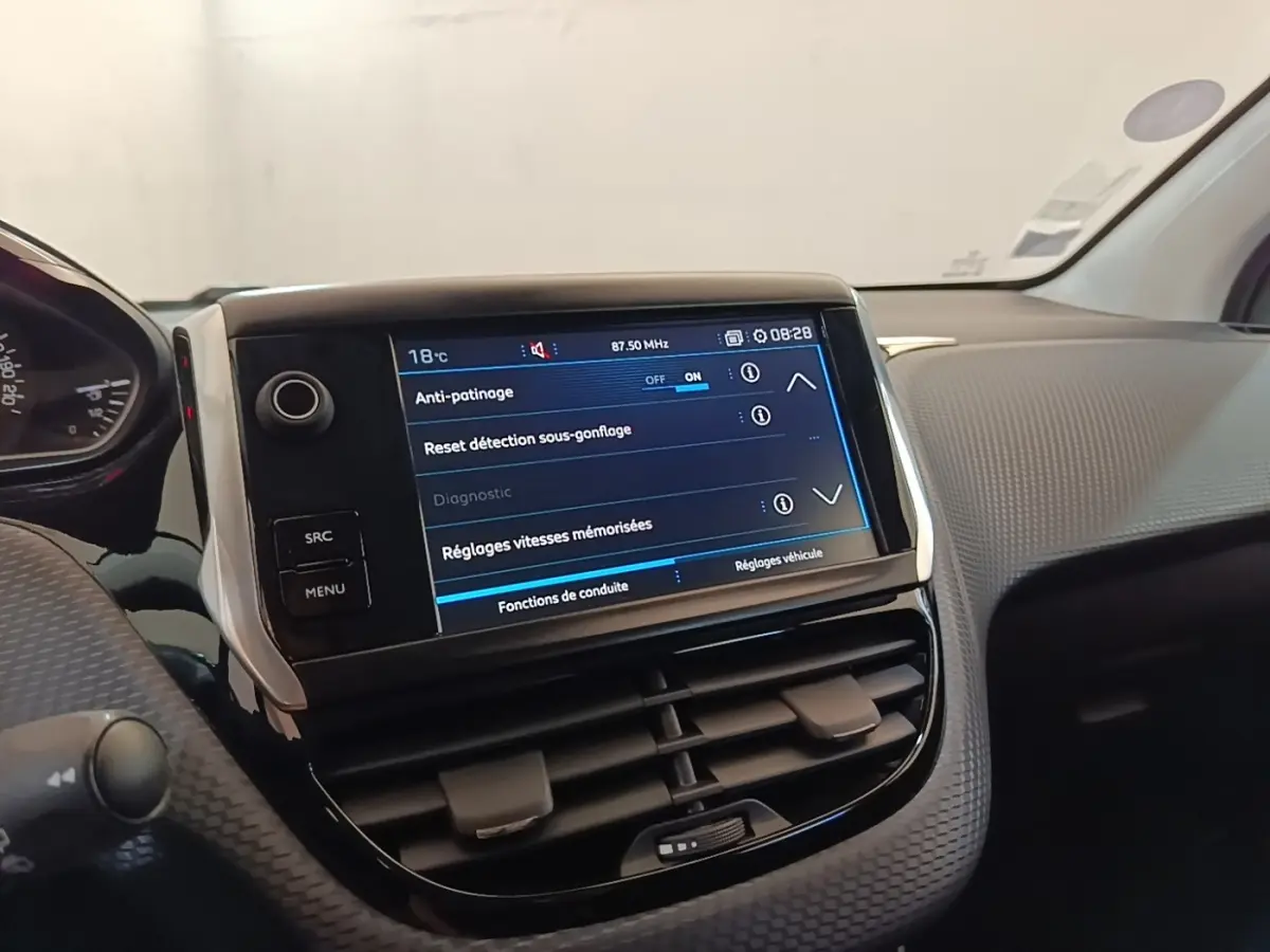 Vue intérieure du tableau de bord de la Peugeot 208 gris clair, avec écran tactile affichant les réglages d'anti-patinage.