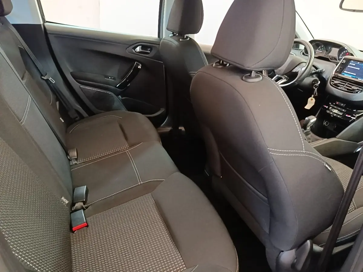 Vue intérieure arrière droite de la Peugeot 208 Puretech 82 Allure 2019, sièges tissu noirs avec surpiqûres blanches.