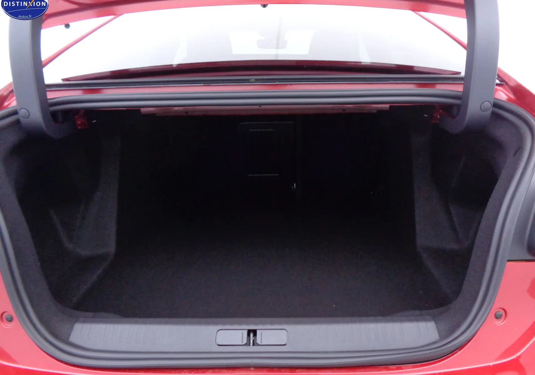 Coffre ouvert vu de l'arrière d'une Citroën C4 X rouge Elixir Métal, espace de rangement spacieux et propre.