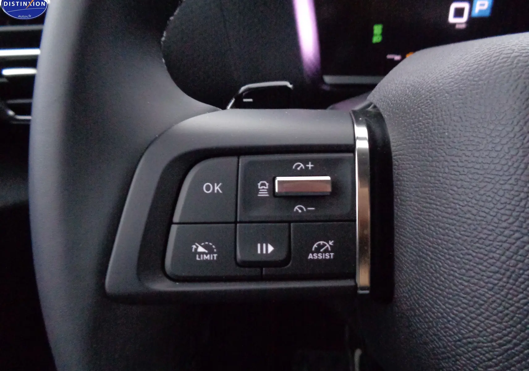 Gros plan sur les commandes au volant à gauche de la Citroën C4 X rouge Elixir Metal 2023, boutons de régulateur et limiteur.