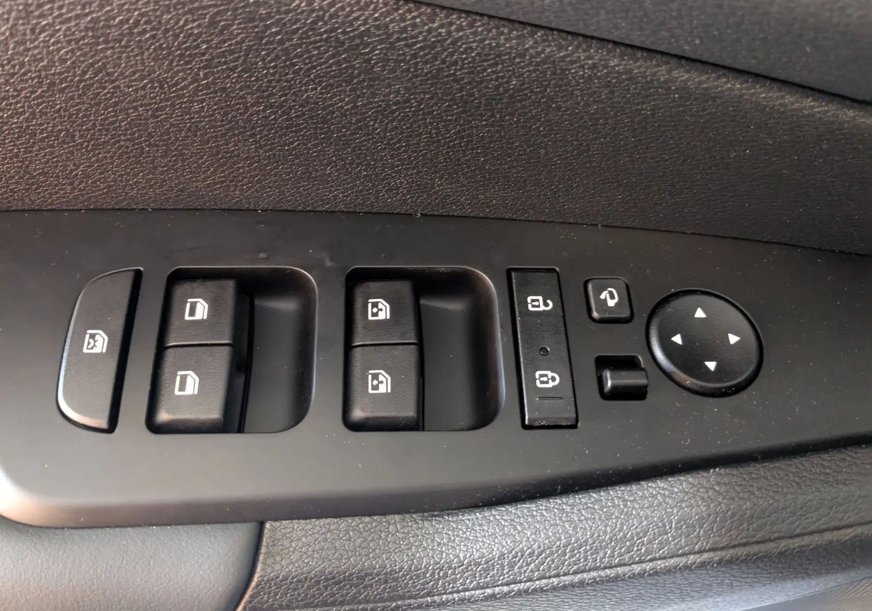 Panneau de commandes des vitres et rétroviseurs côté conducteur du Kia Sportage gris eclipse MY25, intérieur noir.