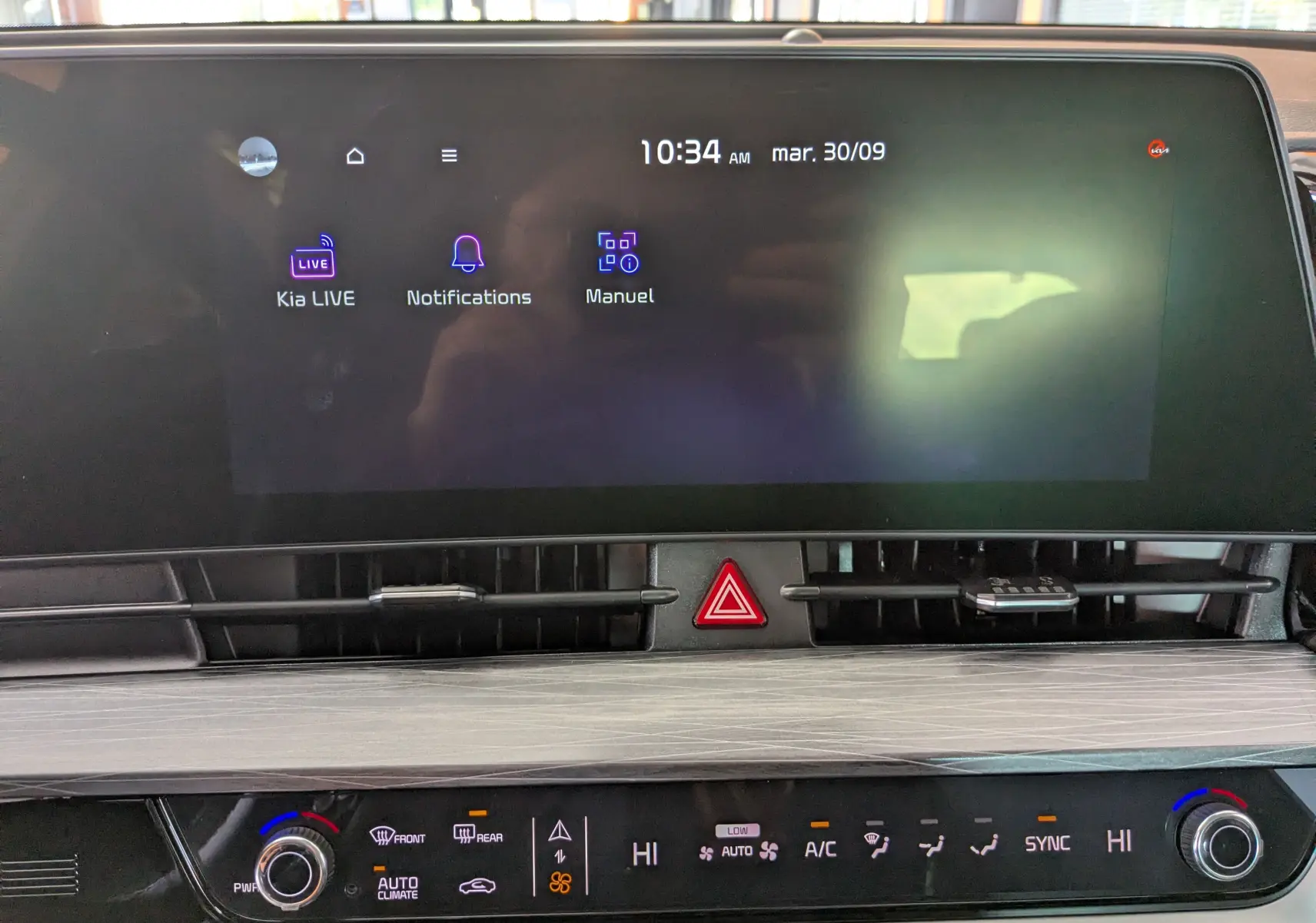 Écran tactile central du Kia Sportage MY25 avec commandes climatisation bizone et bouton warning rouge visible.