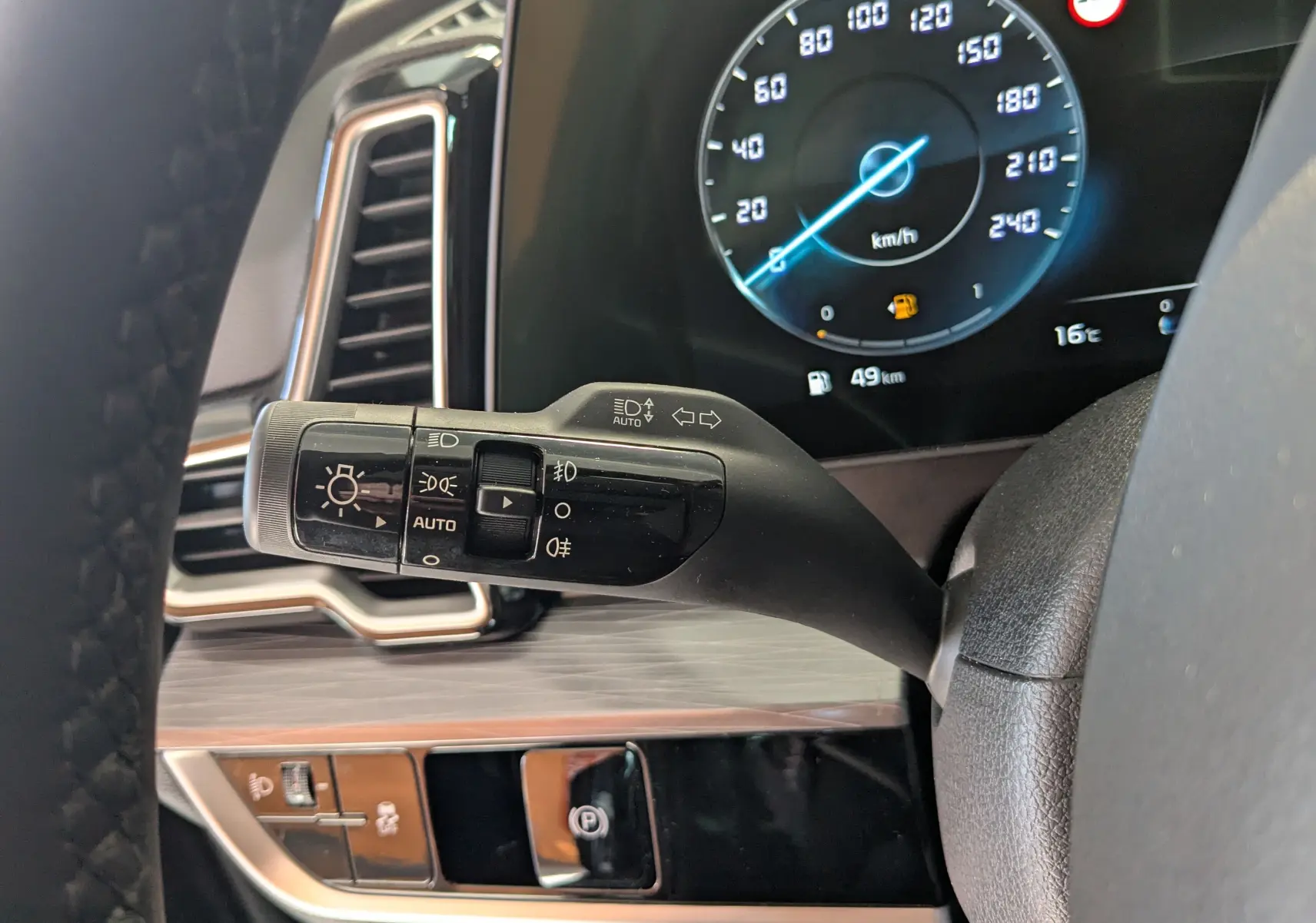 Gros plan sur la commande des phares à gauche du volant dans l'habitacle du Kia Sportage gris eclipse 2025.